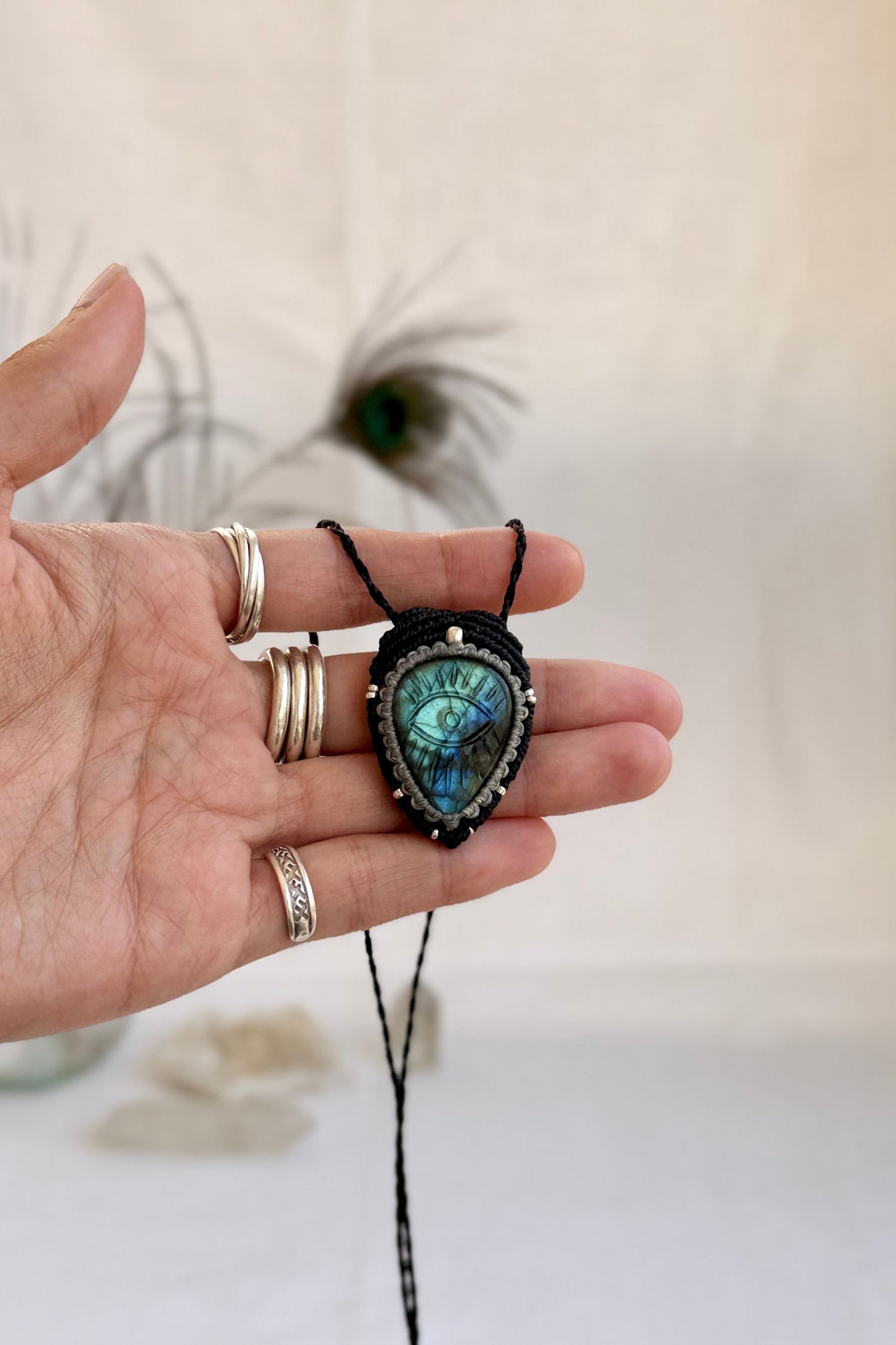 Hand holding handmade Labradorite macrame necklace, showing the scale and carved gemstone details.