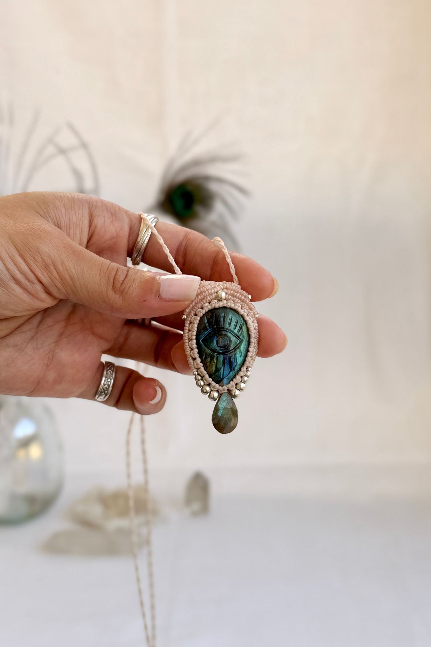 Hand holding handmade Labradorite macrame necklace with a faceted Labradorite gemstone tear, showing the scale and carved gemstone details.