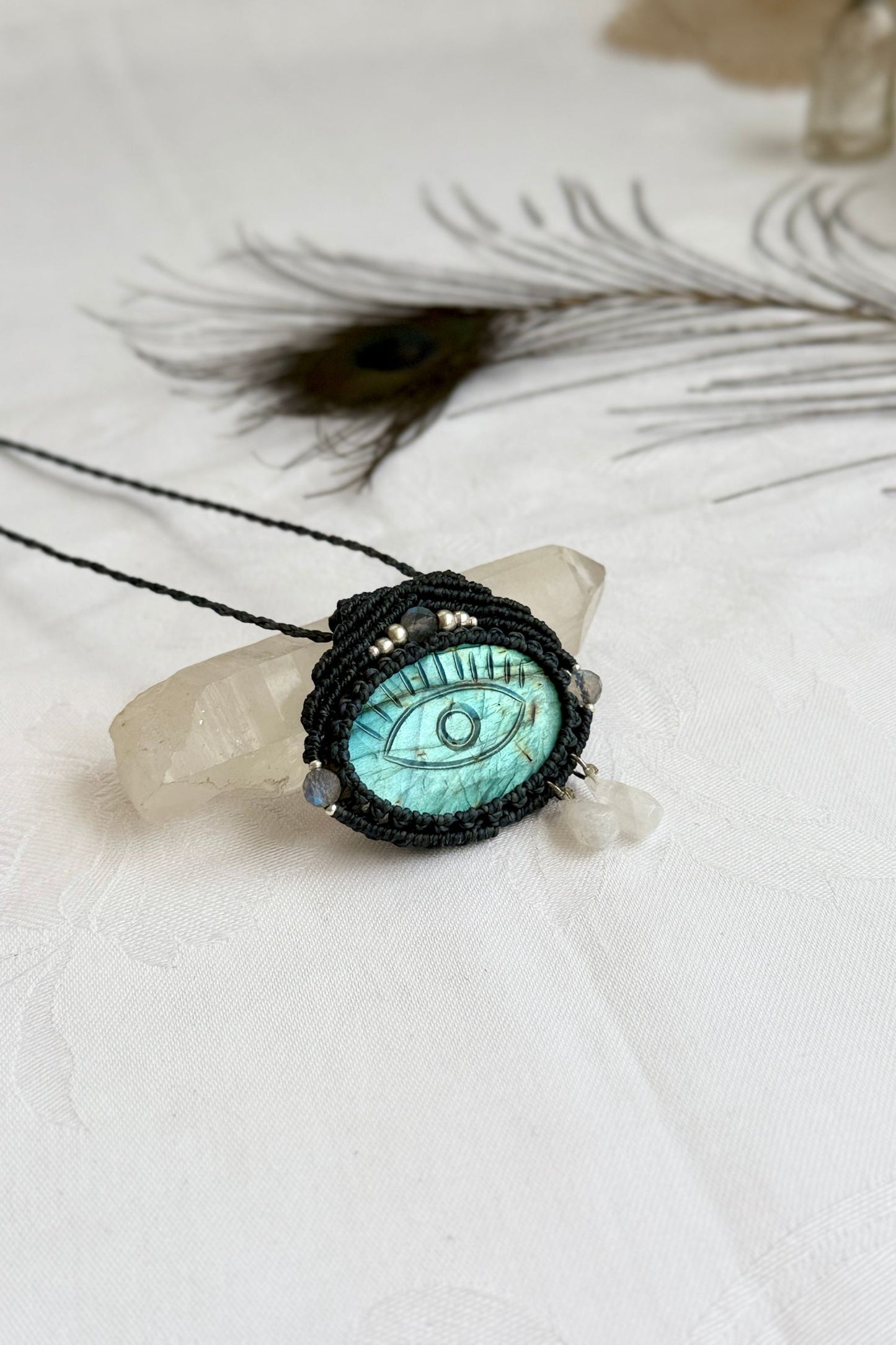 One-of-a-kind Labradorite necklace with carved protective eye, laid flat to highlight its unique shimmer and design.
