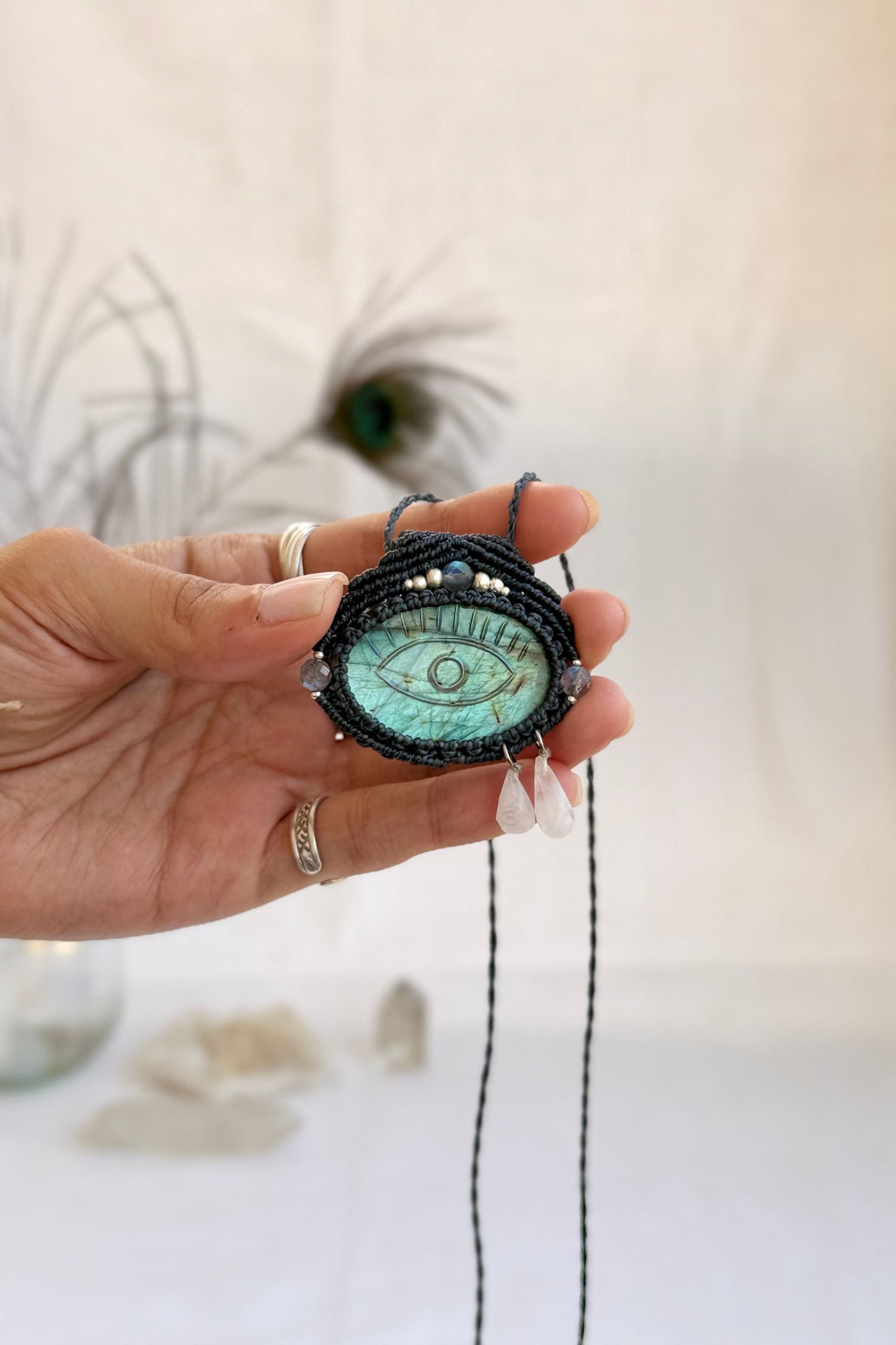 Hand holding handmade Labradorite macrame necklace with dangling Moonstone tears, showing the scale and carved gemstone details.