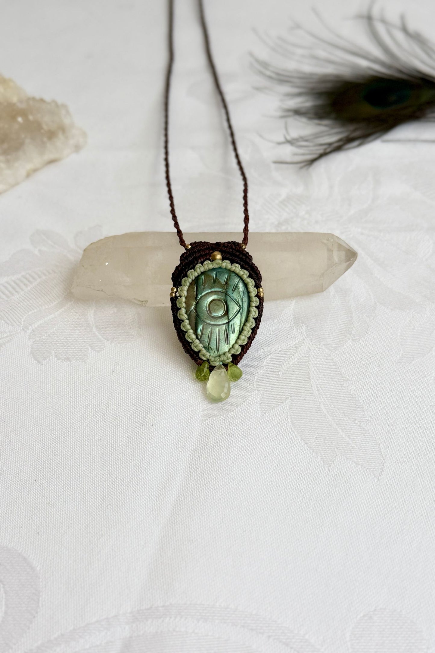 One-of-a-kind Labradorite necklace with carved protective eye, laid flat to highlight its unique shimmer and design.