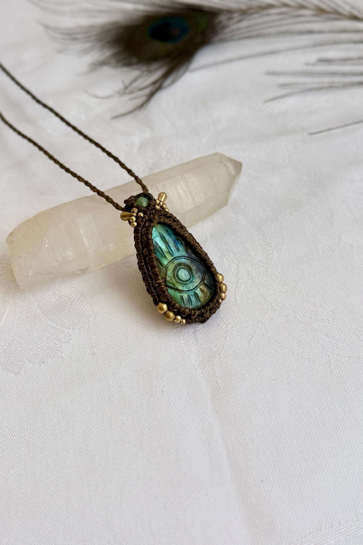 One-of-a-kind Labradorite necklace with carved protective eye, laid flat to highlight its unique shimmer and design.