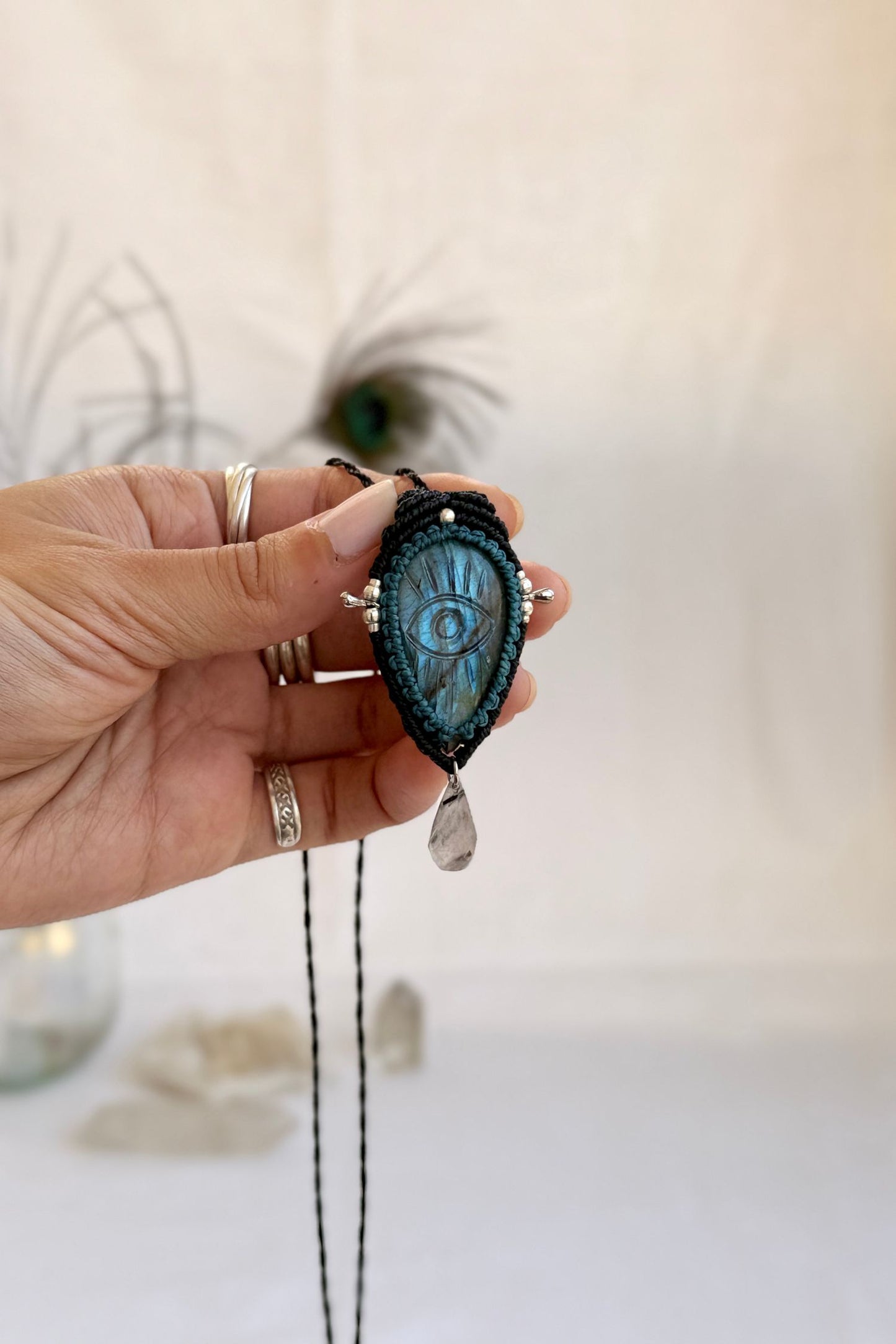 Hand holding handmade Labradorite macrame necklace with dangling Tourmaline Quartz tear, showing the scale and carved gemstone details.