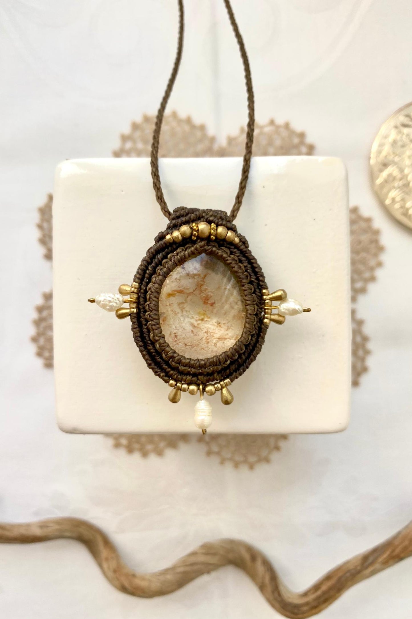 Artistic jewelry display of a one-of-a-kind macrame necklace, featuring hand-selected gemstones in a timeless and elegant design.