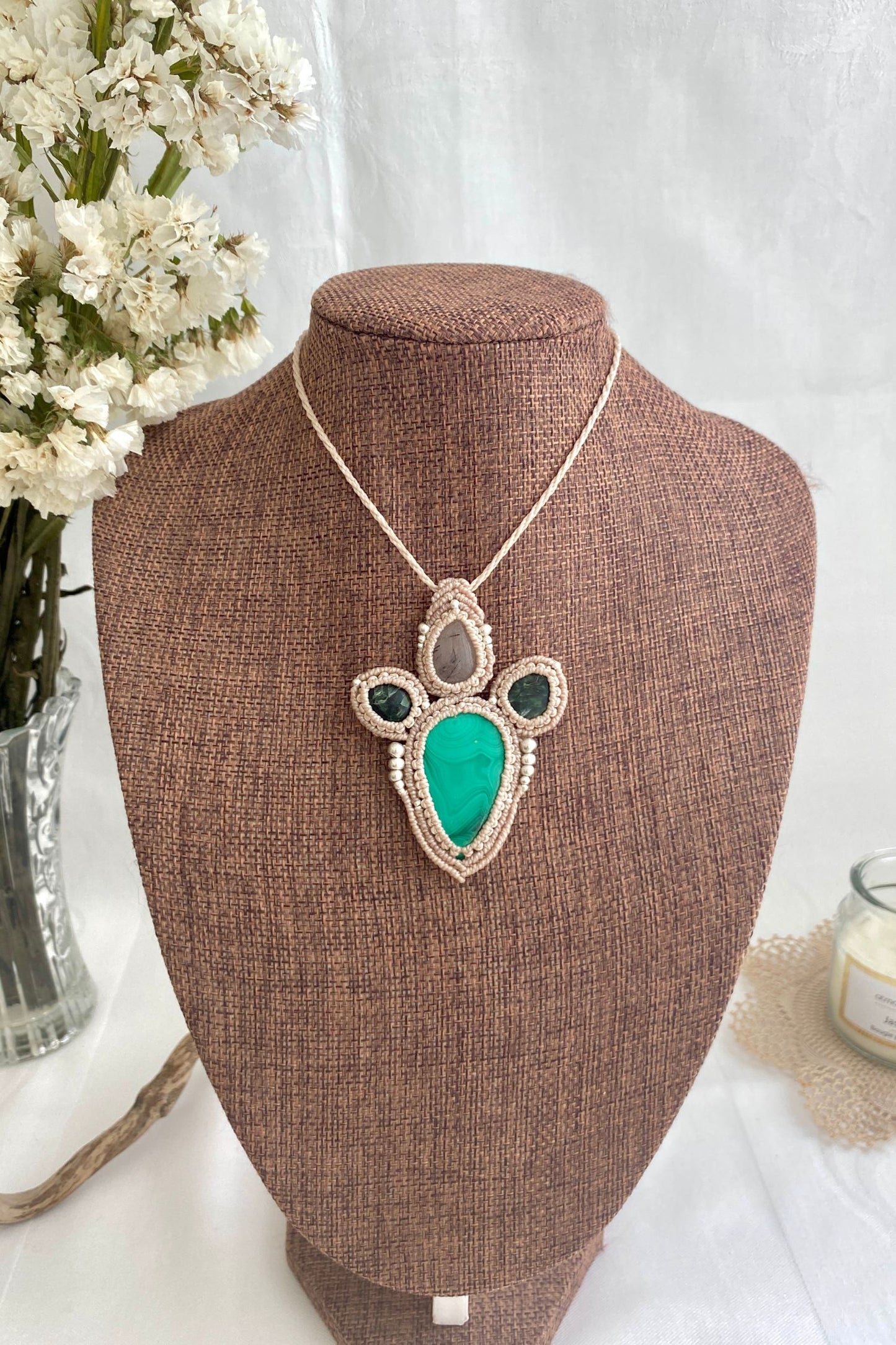 Artistic jewelry display of a one-of-a-kind macrame necklace, featuring hand-selected gemstones in a timeless and elegant design.