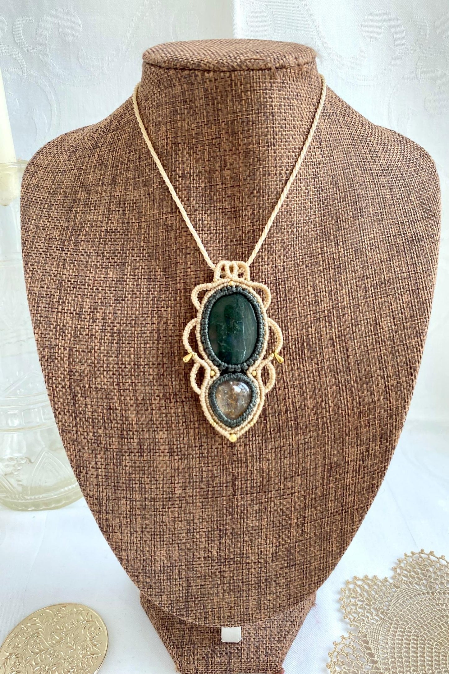 Artistic jewelry display of a one-of-a-kind macrame necklace, featuring hand-selected gemstones in a timeless and elegant design.