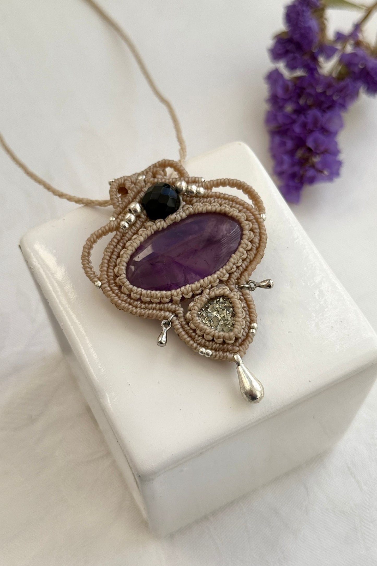 Detailed close-up of Amethyst and Raw Druzy Pyrite gemstones in a handmade macrame necklace. Showcasing natural textures and gemstone glow.