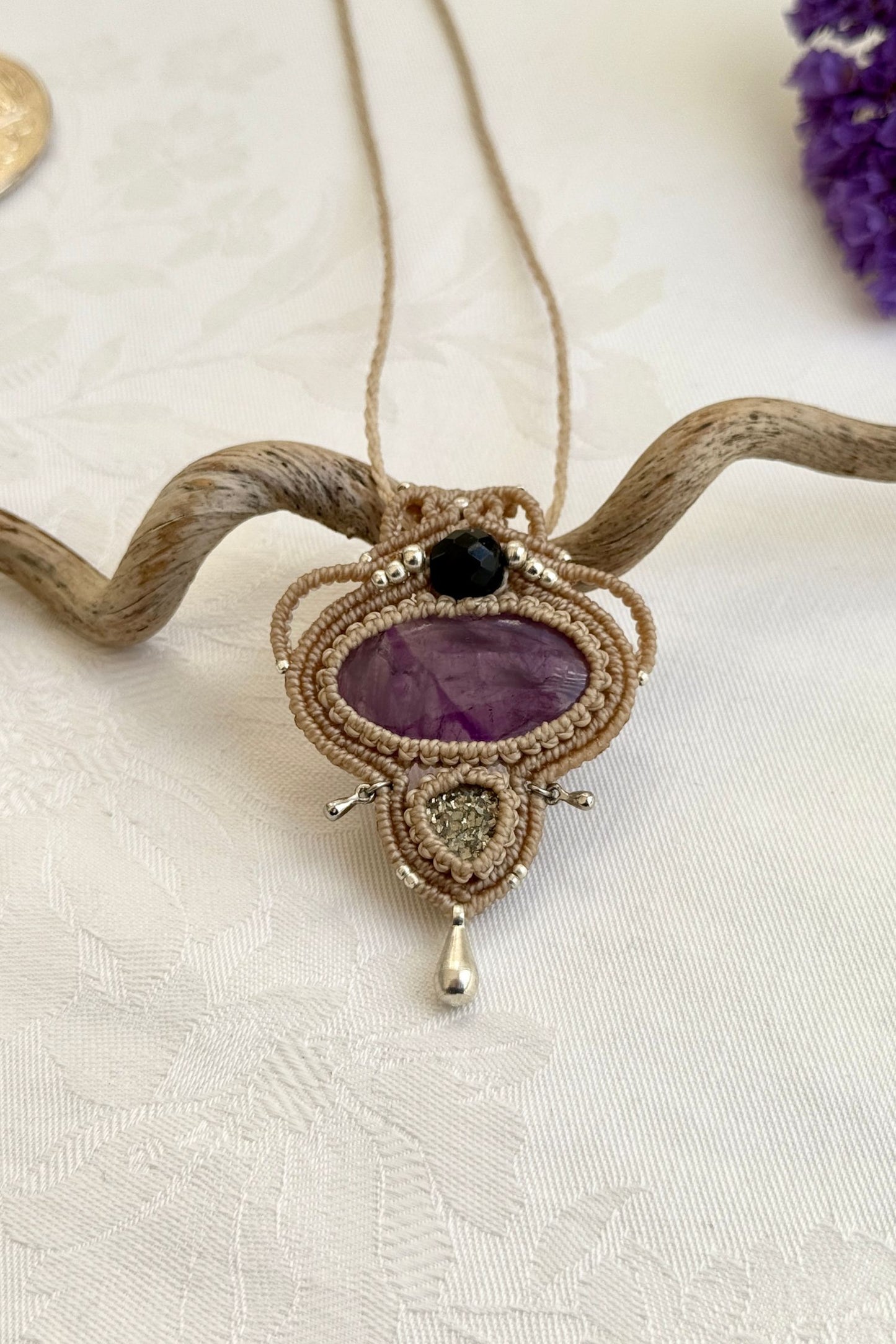 Close-up of the Amethyst and Raw Druzy Pyrite macrame necklace in a unique setting. Highlighting the craftsmanship and gemstones details.