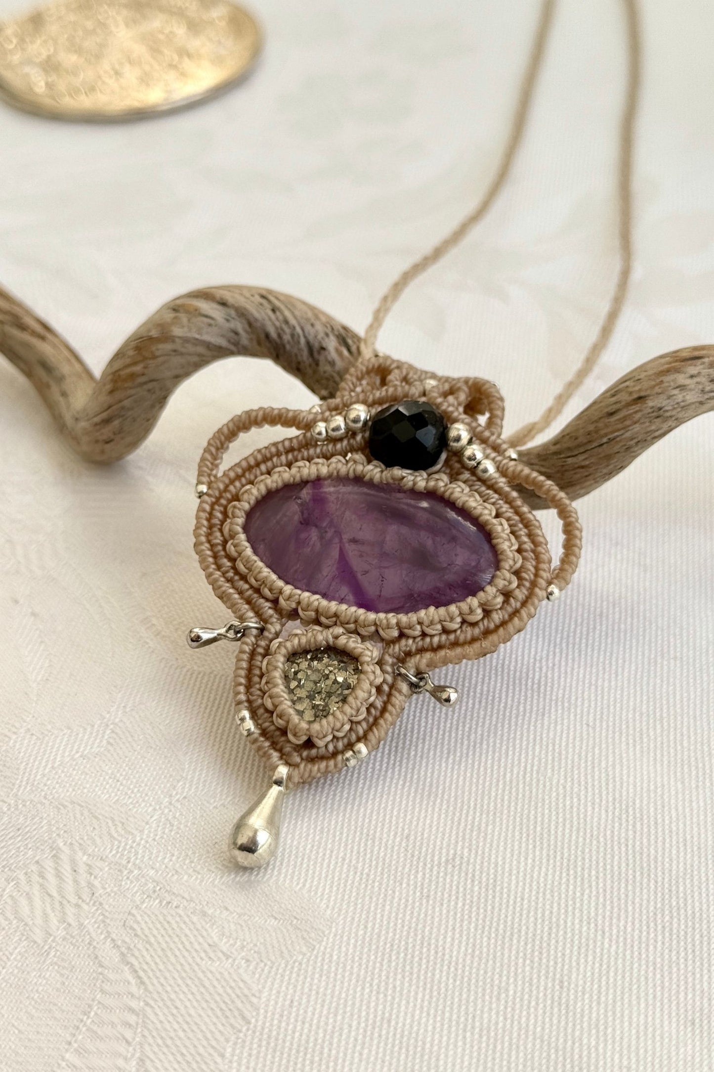 Side-angle view of the handmade macrame necklace with Amethyst and Raw Druzy Pyrite. Showcasing depth, knotting details, and stone textures.