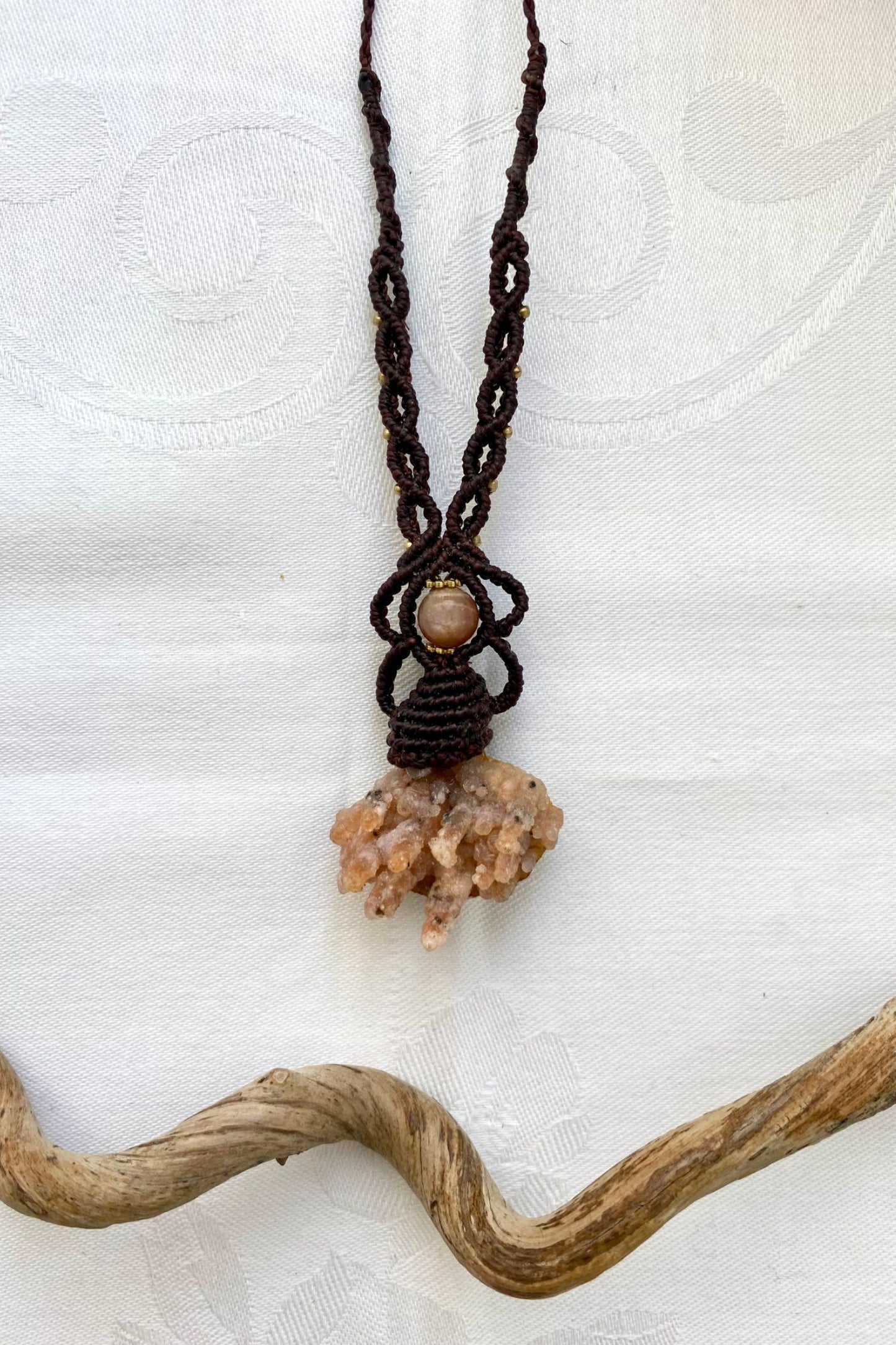 Artistic jewelry display of a one-of-a-kind macrame necklace, featuring hand-selected gemstones in a timeless and elegant design.