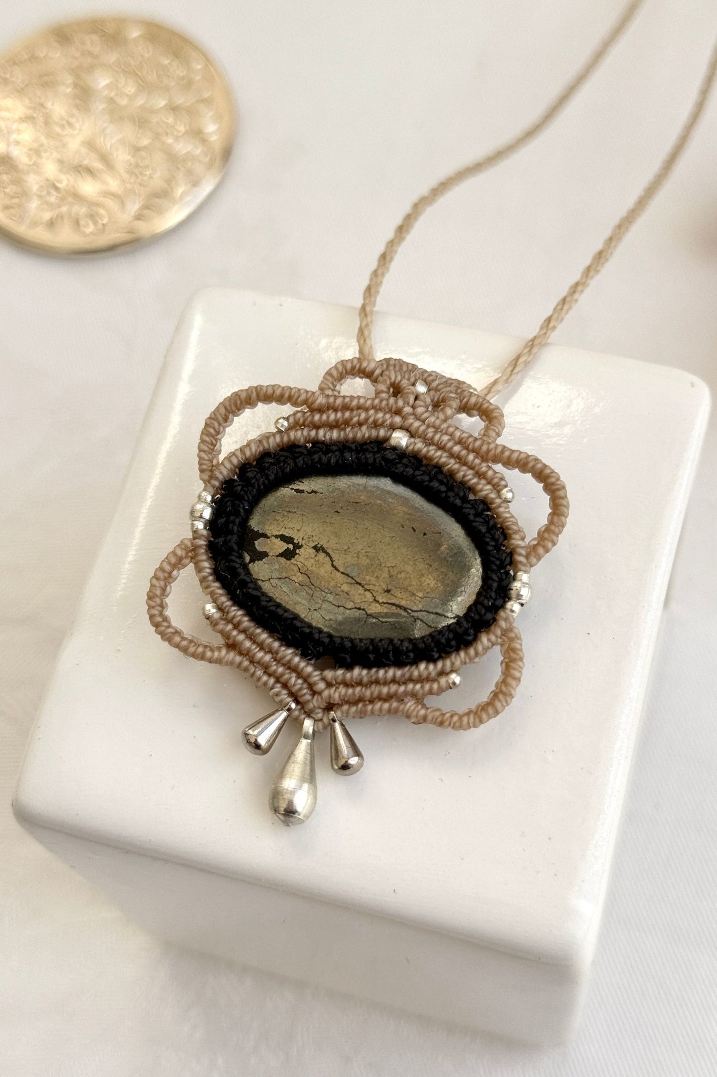 Detailed close-up of Pyrite gemstone in a handmade macrame necklace. Showcasing natural textures and gemstone glow.