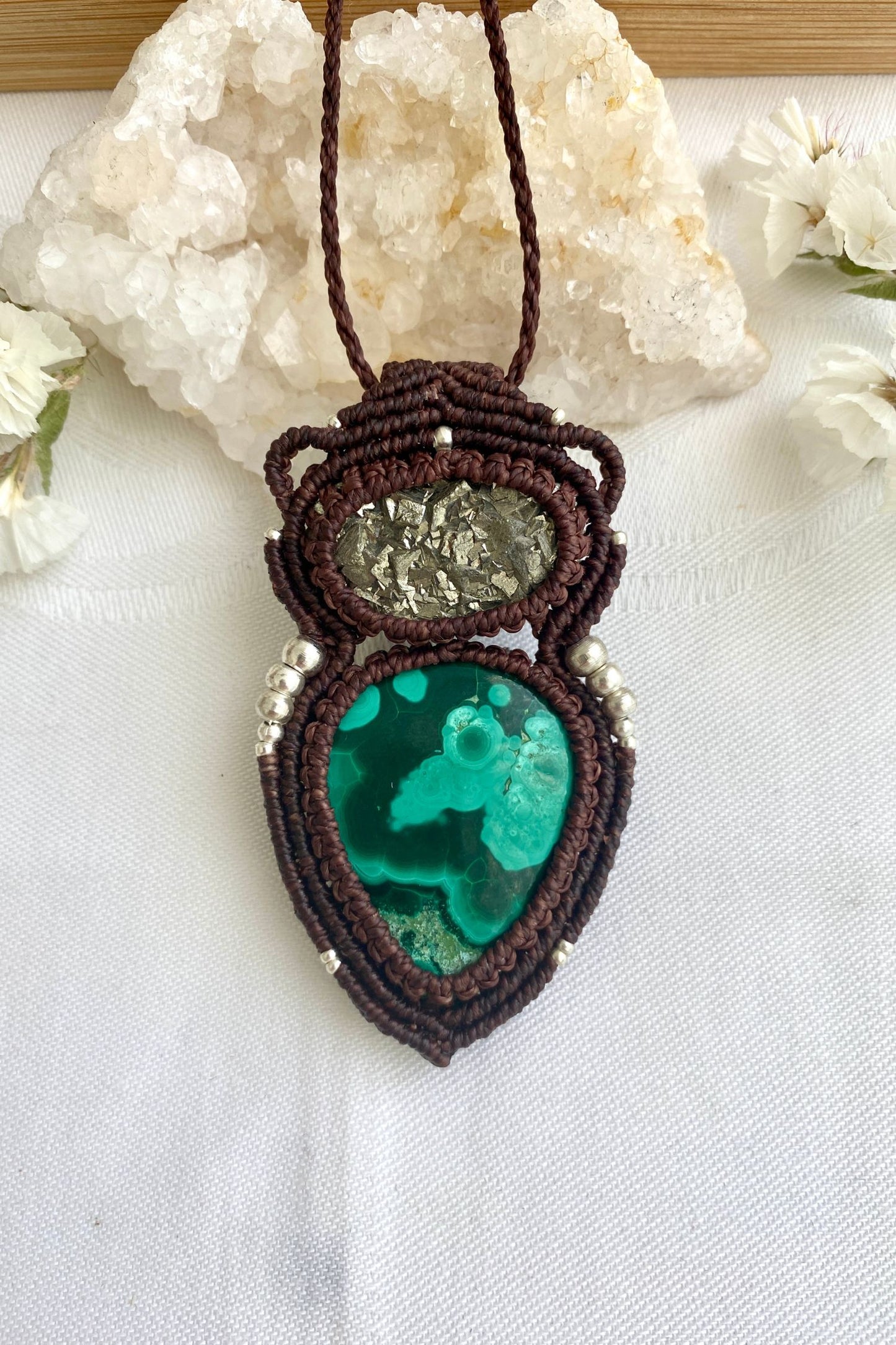 Handmade macrame necklace with natural malachite and raw pyrite on a clean white background, emphasizing the unique swirls of malachite.