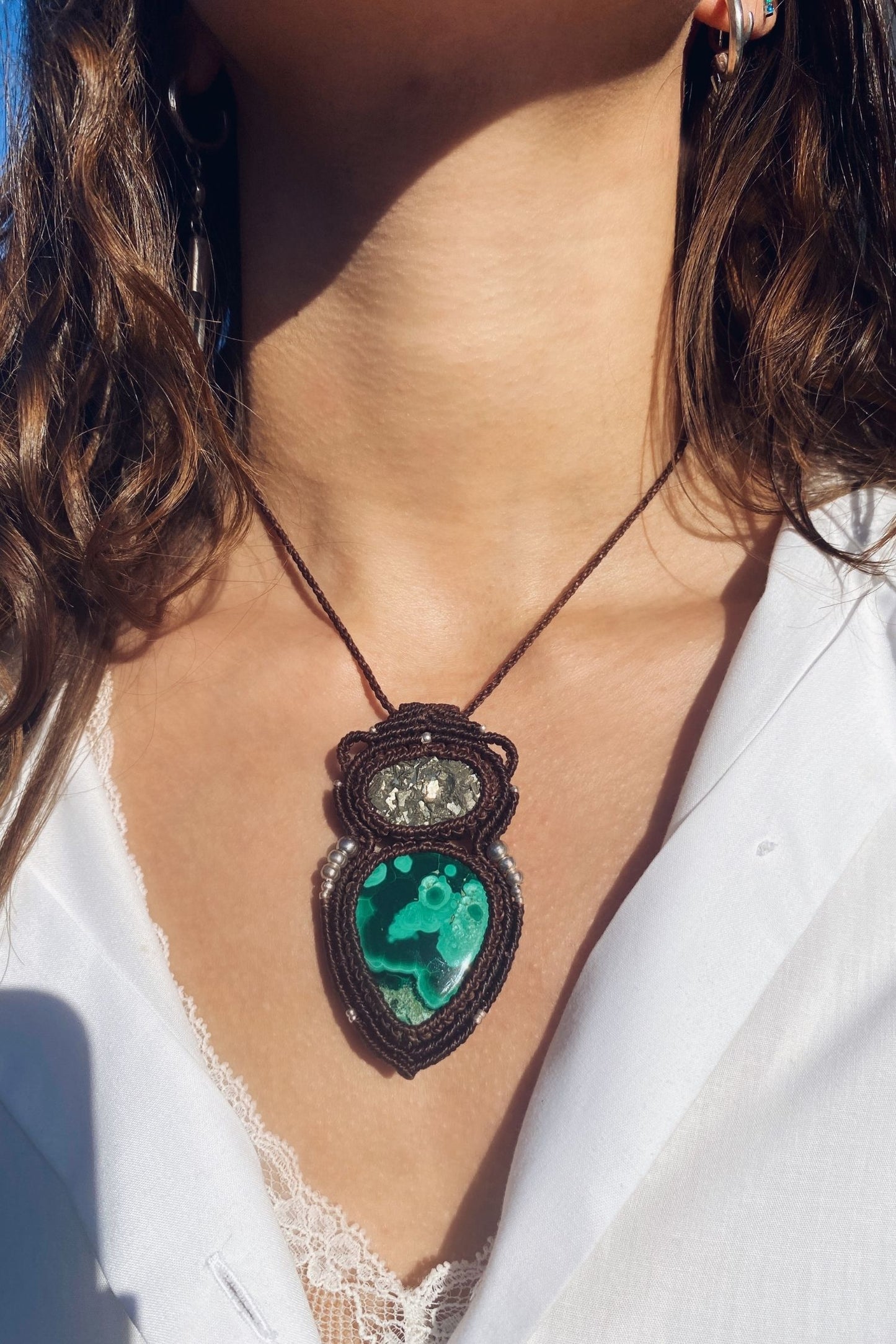 Model wearing a handmade macrame necklace with natural malachite and raw pyrite, highlighting the unique design and gemstone colors.