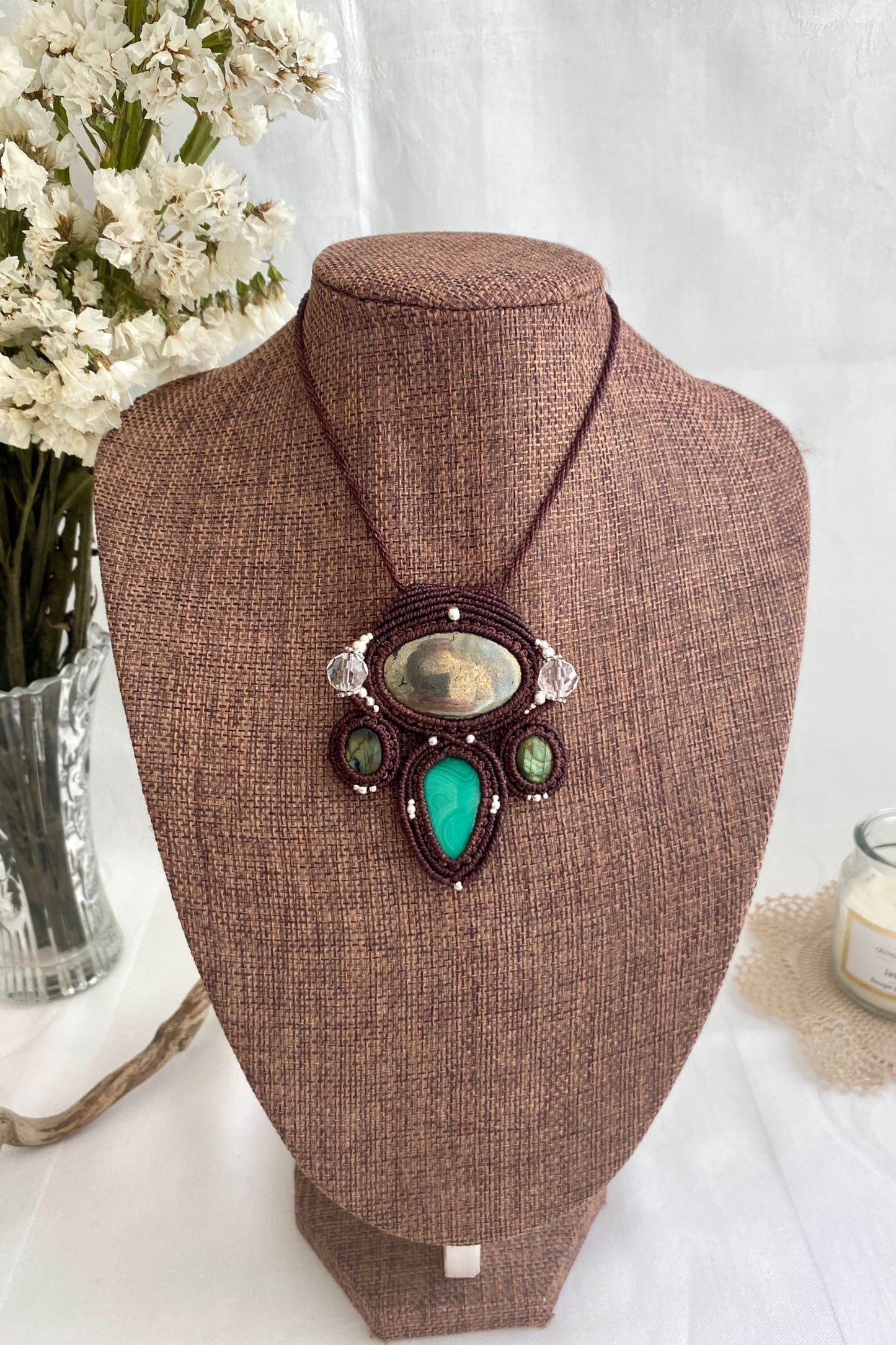 Artistic jewelry display of a one-of-a-kind macrame necklace, featuring hand-selected gemstones in a timeless and elegant design.