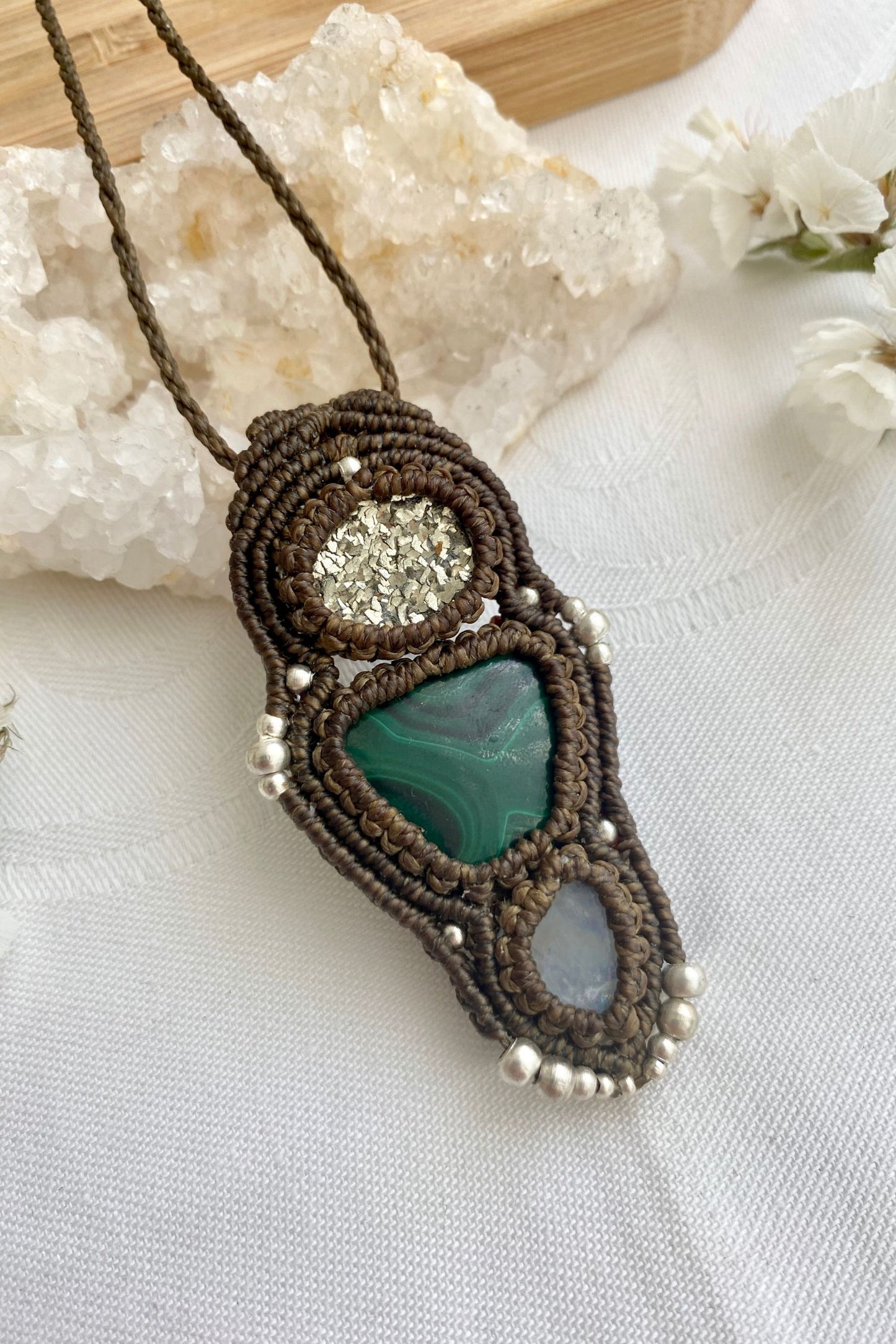 Side angle of the handcrafted macrame necklace, highlighting the detailed craftsmanship and the rich colors of Raw Pyrite, Malachite and Moonstone gemstones.