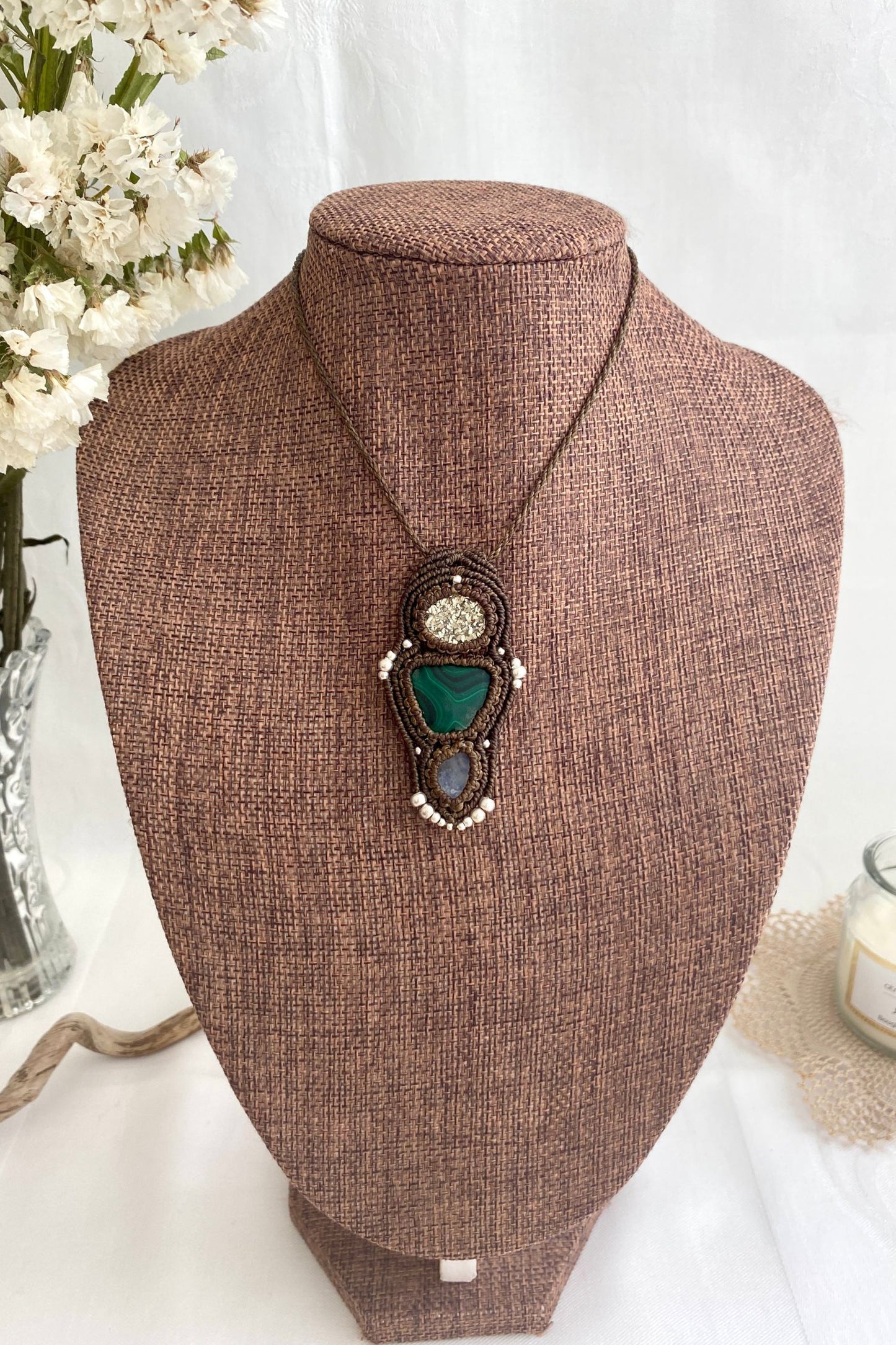 Artistic jewelry display of a one-of-a-kind macrame necklace, featuring hand-selected gemstones in a timeless and elegant design.