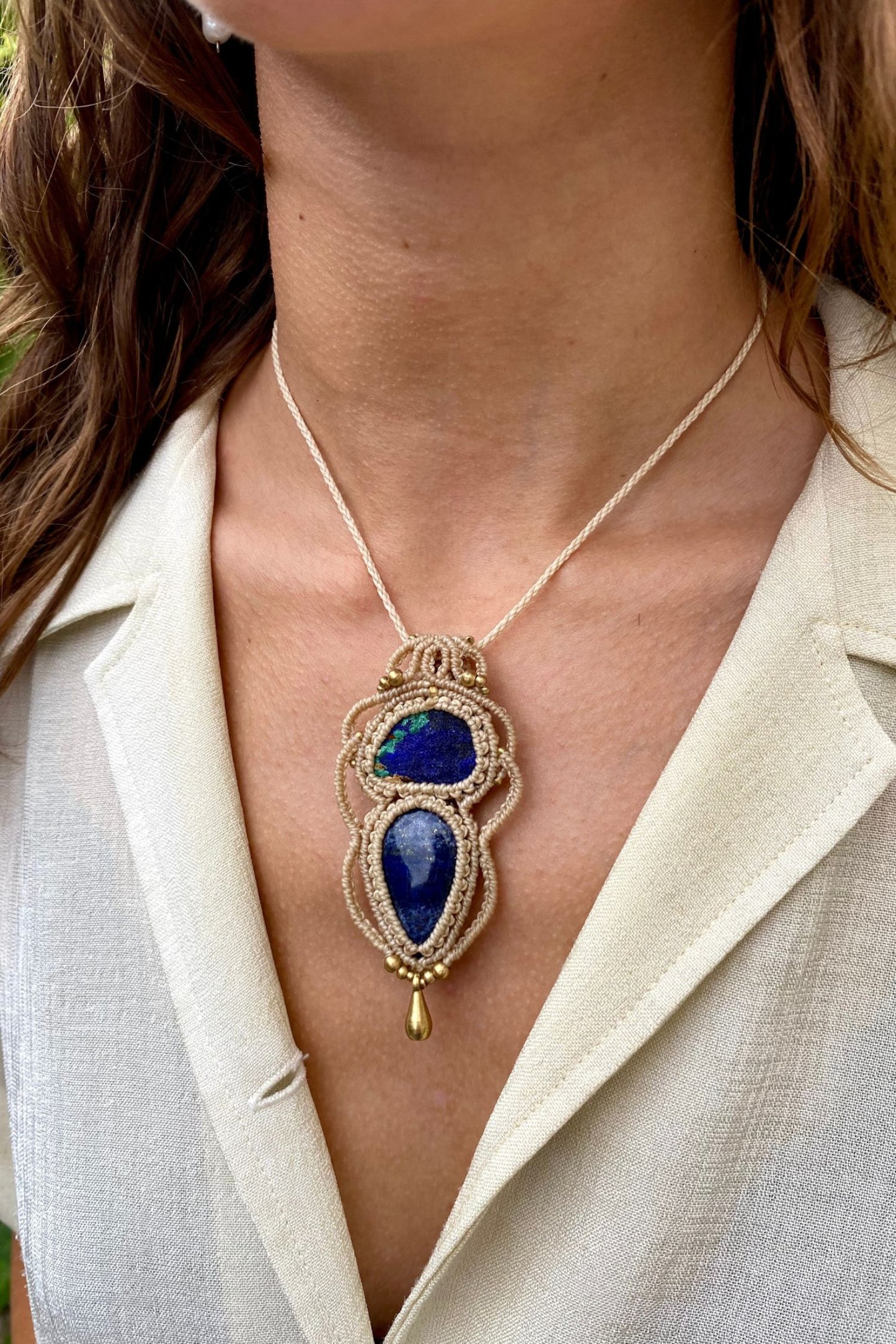 Artistic jewelry display of a one-of-a-kind macrame necklace, featuring hand-selected gemstones in a timeless and elegant design.