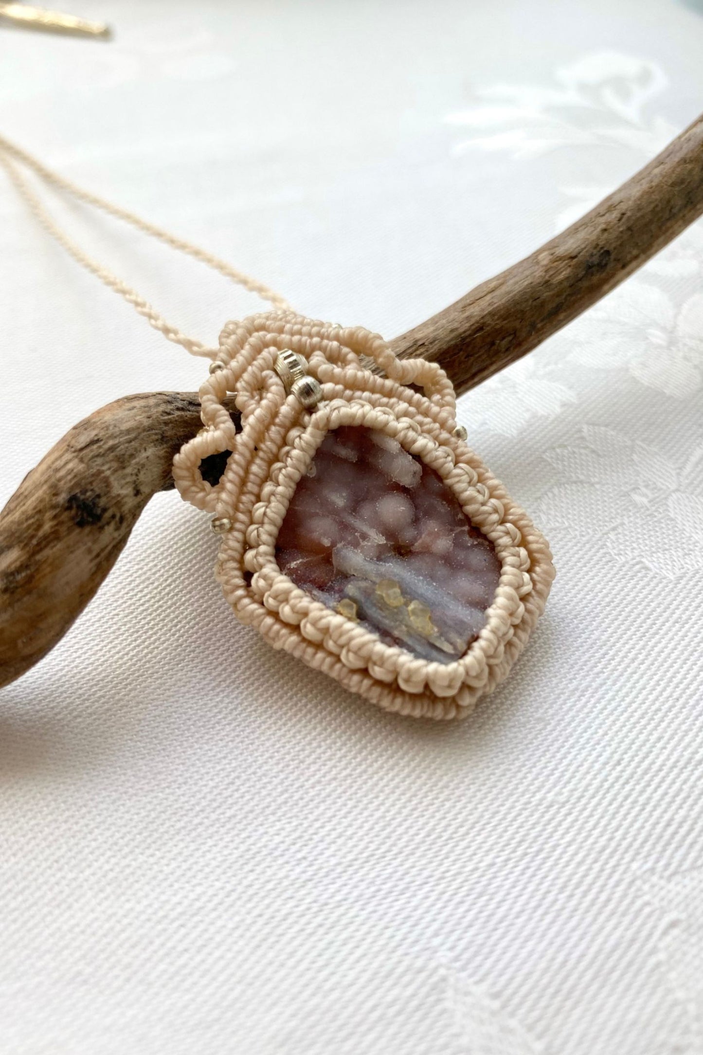 Side angle of the handcrafted macrame necklace, highlighting the detailed craftsmanship and the rich colors of Raw Pink Chalcedony Stalactite gemstone.
