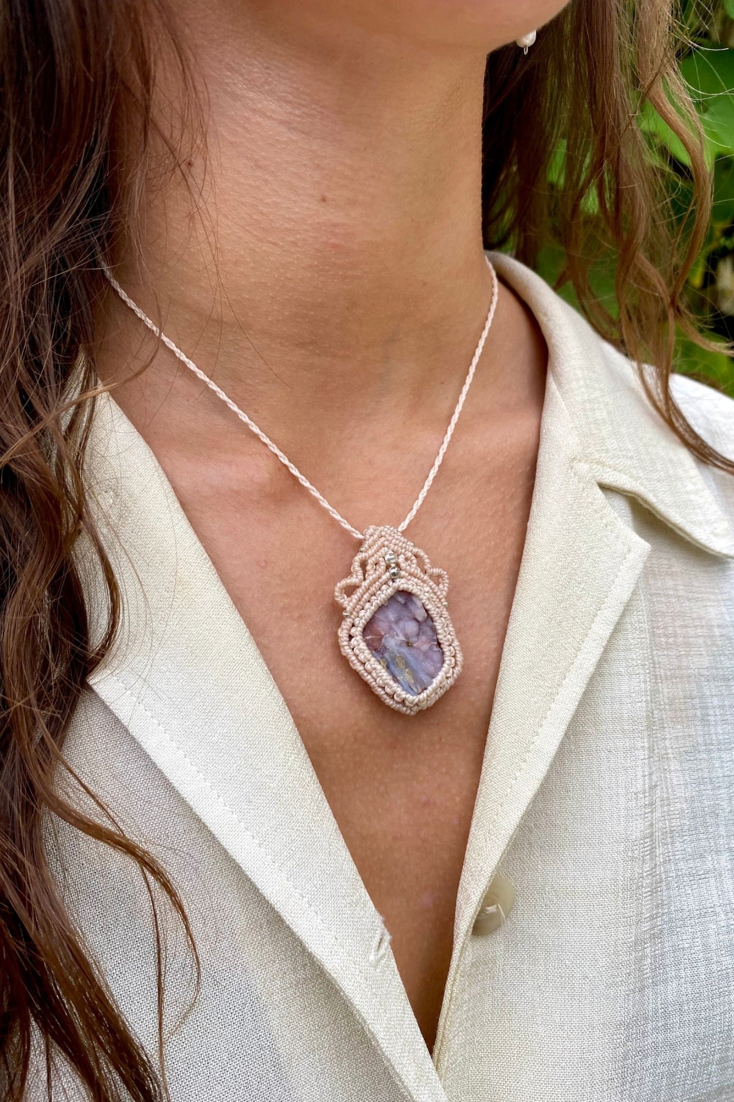 Artistic jewelry display of a one-of-a-kind macrame necklace, featuring hand-selected gemstones in a timeless and elegant design.