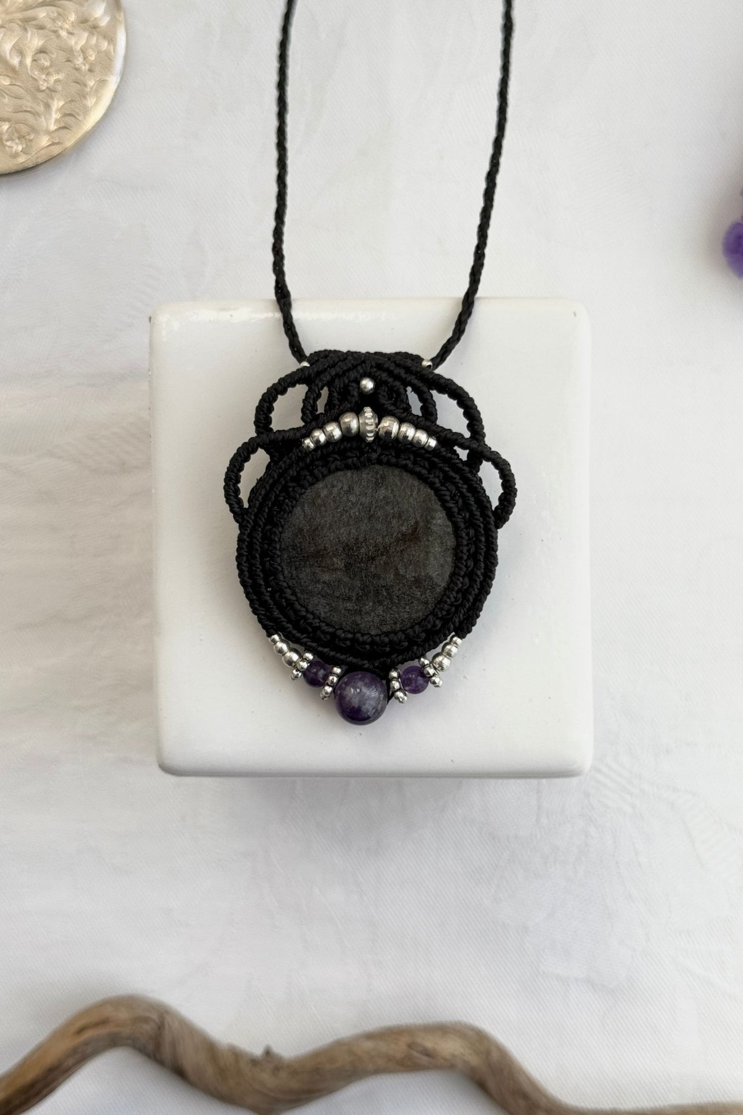 Handmade macrame necklace with Silver Sheen Obsidian and Amethyst gemstones, part of the Nocturnal Collection. One-of-a-kind design, laid flat for an artistic display.