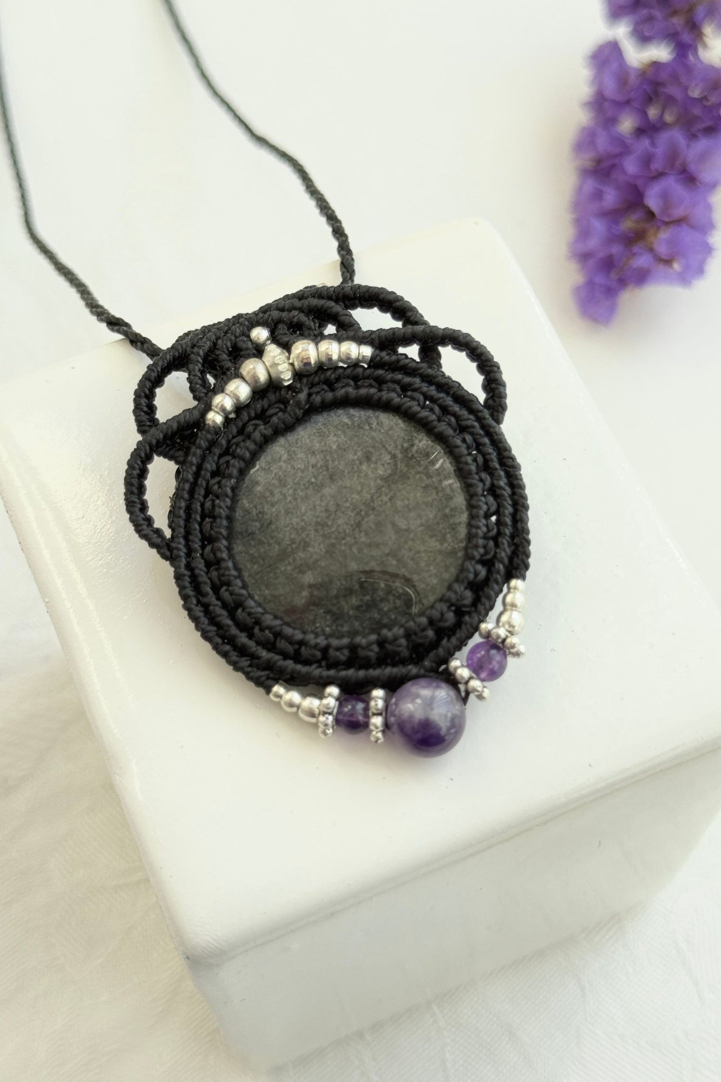 Detailed close-up of Silver Sheen Obsidian and Amethyst gemstones in a handmade macrame necklace. Showcasing natural textures and gemstone glow.