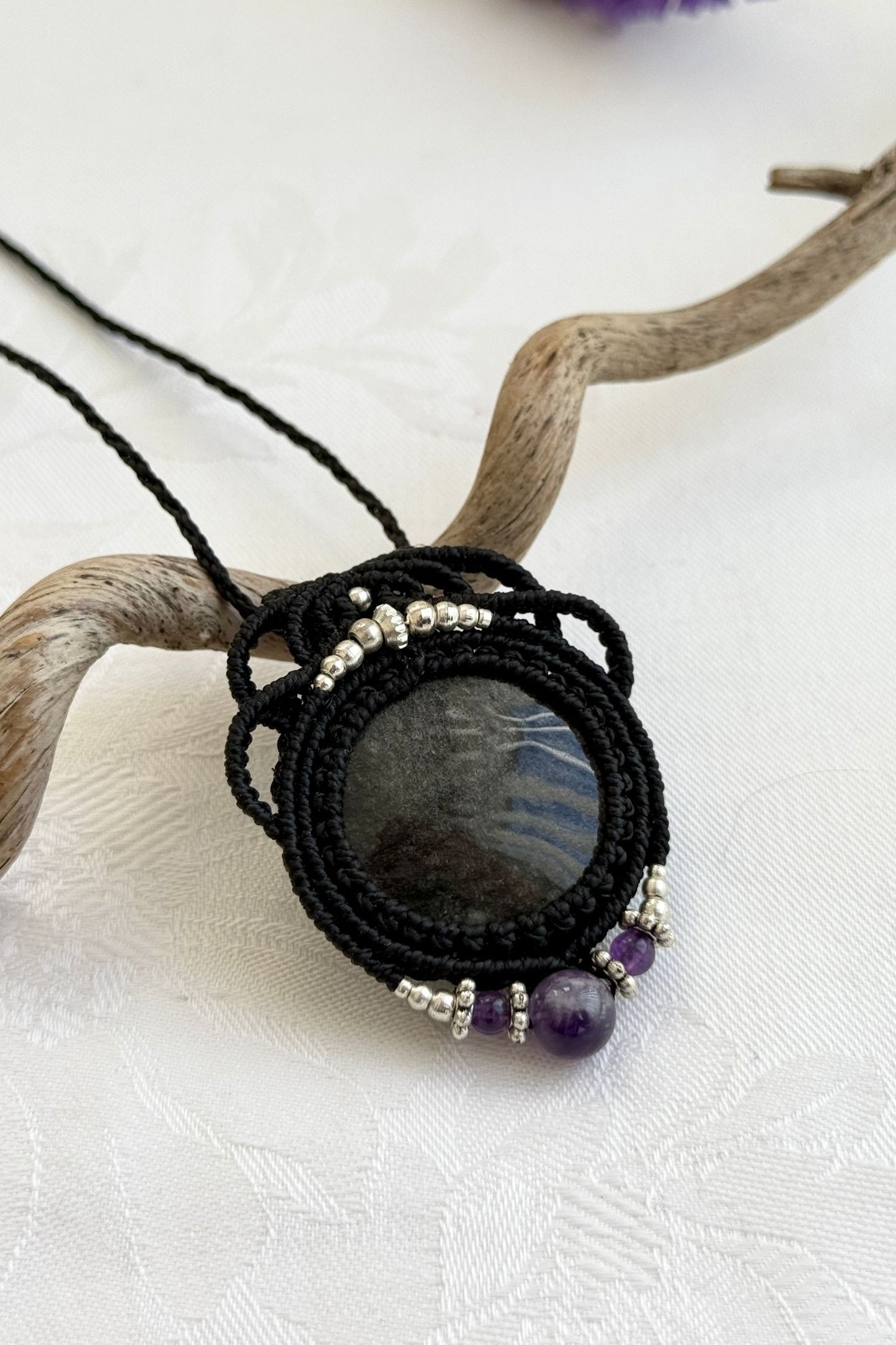 Side-angle view of the handmade macrame necklace with Silver Sheen Obsidian and Amethyst. Showcasing depth, knotting details, and stone textures.