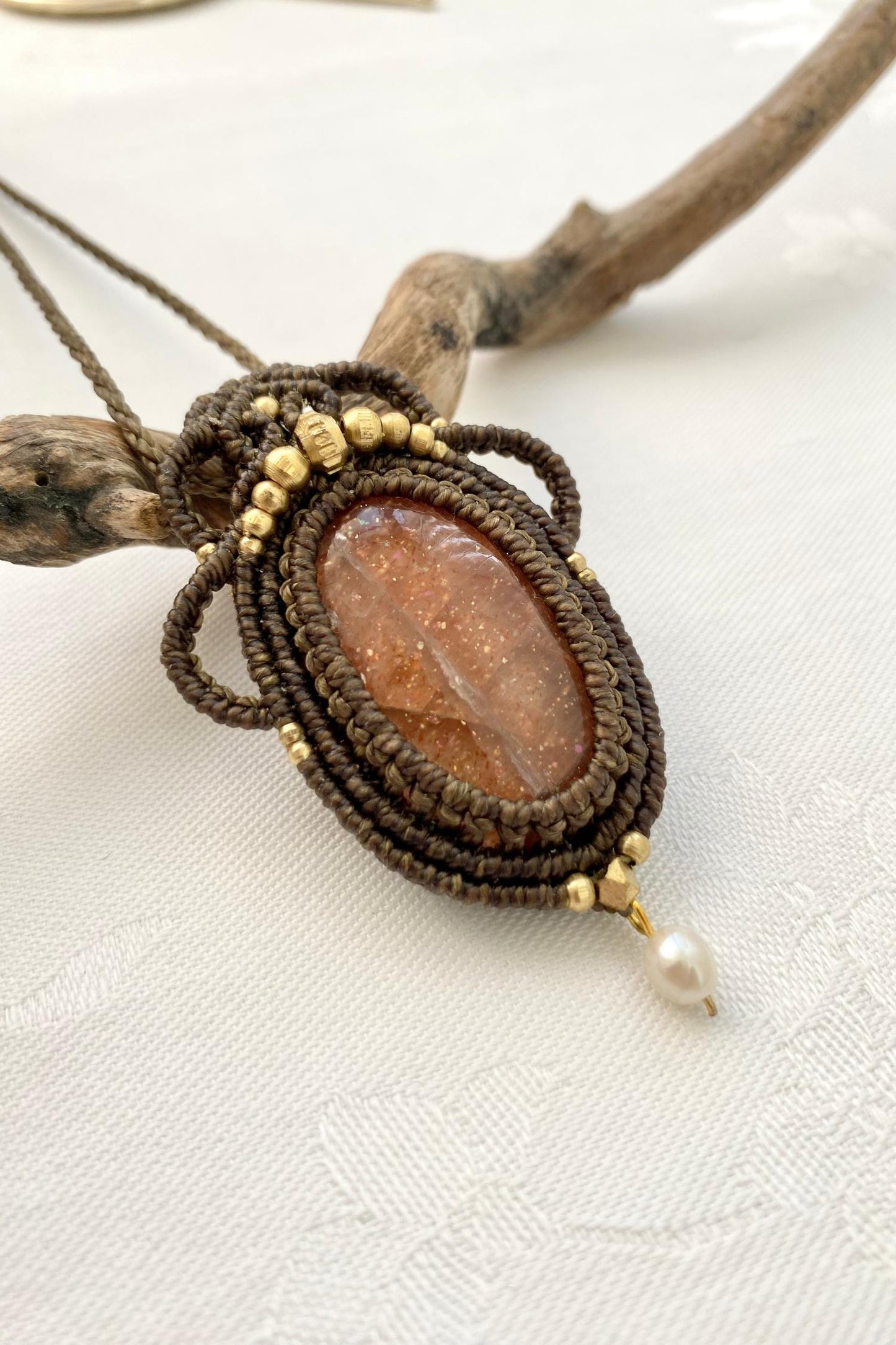 Side angle of the handcrafted macrame necklace, highlighting the detailed craftsmanship and the rich colors of Sunstone gemstone and Pearl.