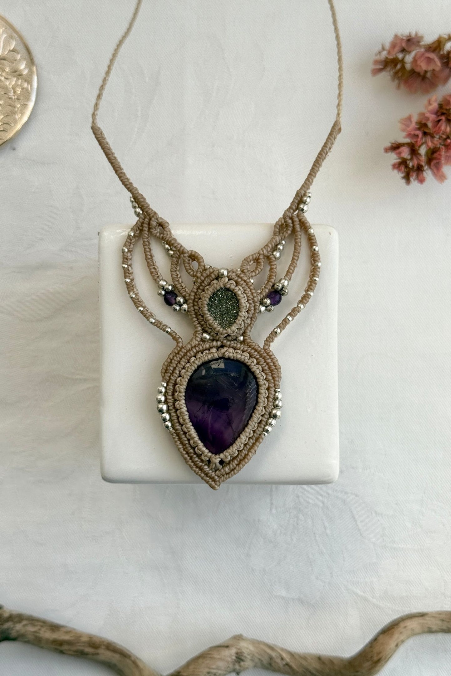 Handmade macrame necklace with Amethyst and Druzy Pyrite gemstones, part of the Nocturnal Collection. One-of-a-kind design, laid flat for an artistic display.