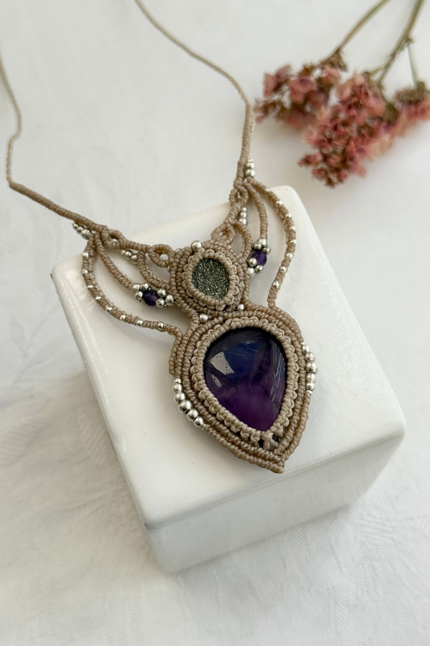 Detailed close-up of Amethyst and Druzy Pyrite gemstones in a handmade macrame necklace. Showcasing natural textures and gemstone glow.