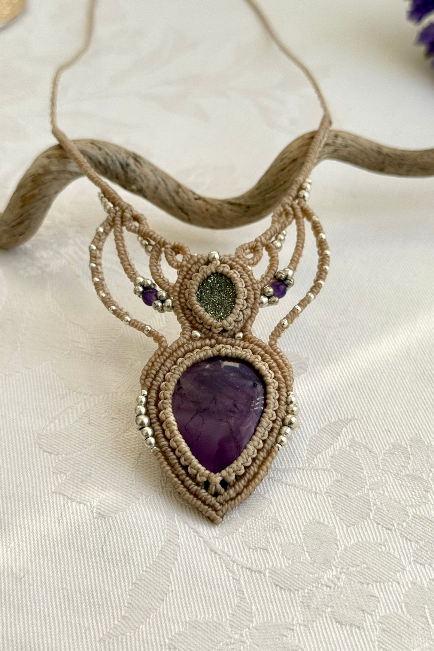 Close-up of the Amethyst and Druzy Pyrite macrame necklace in a unique setting. Highlighting the craftsmanship and gemstone details.