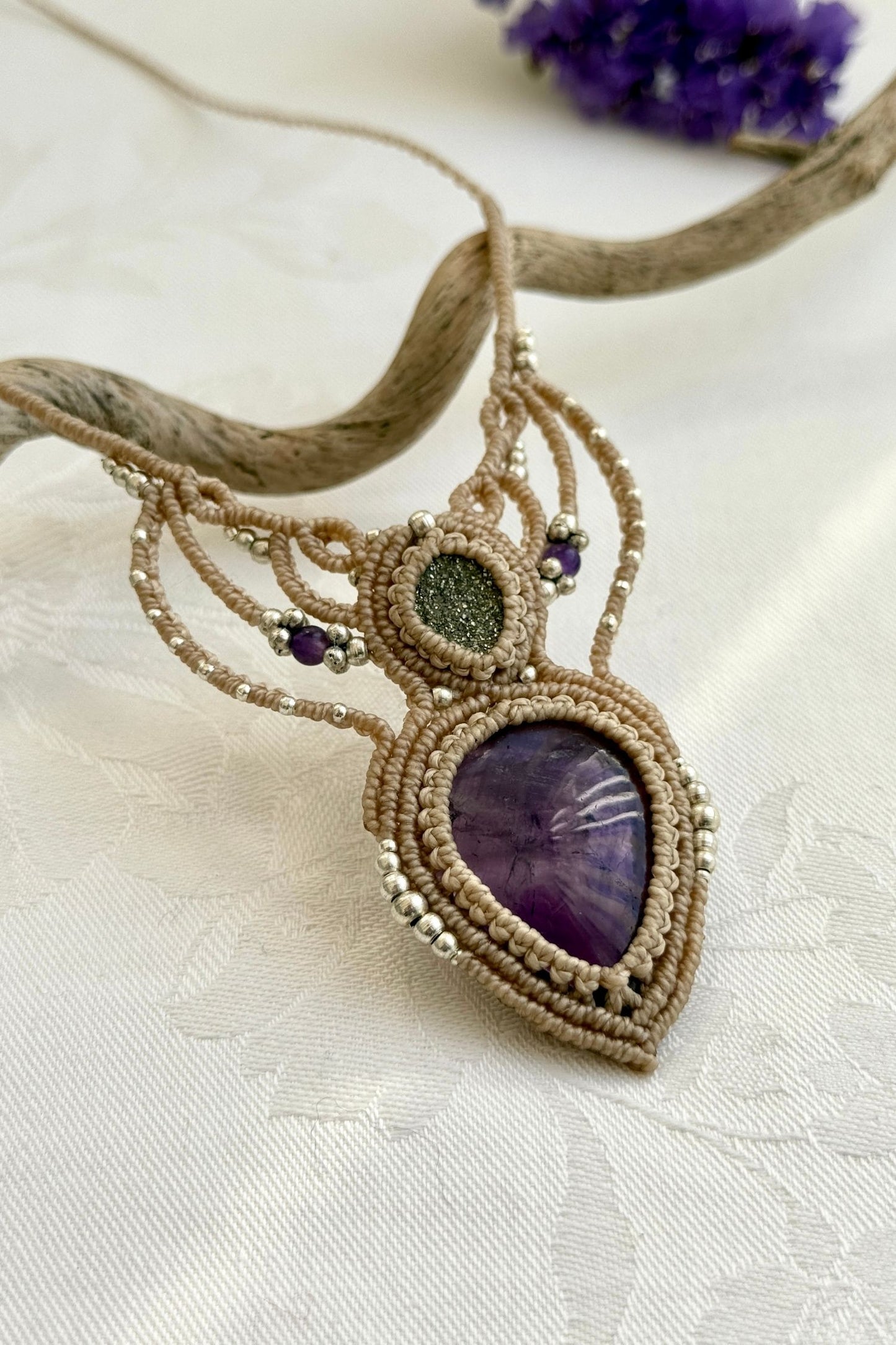 Side-angle view of the handmade macrame necklace with Amethyst and Druzy Pyrite. Showcasing depth, knotting details, and stone textures.
