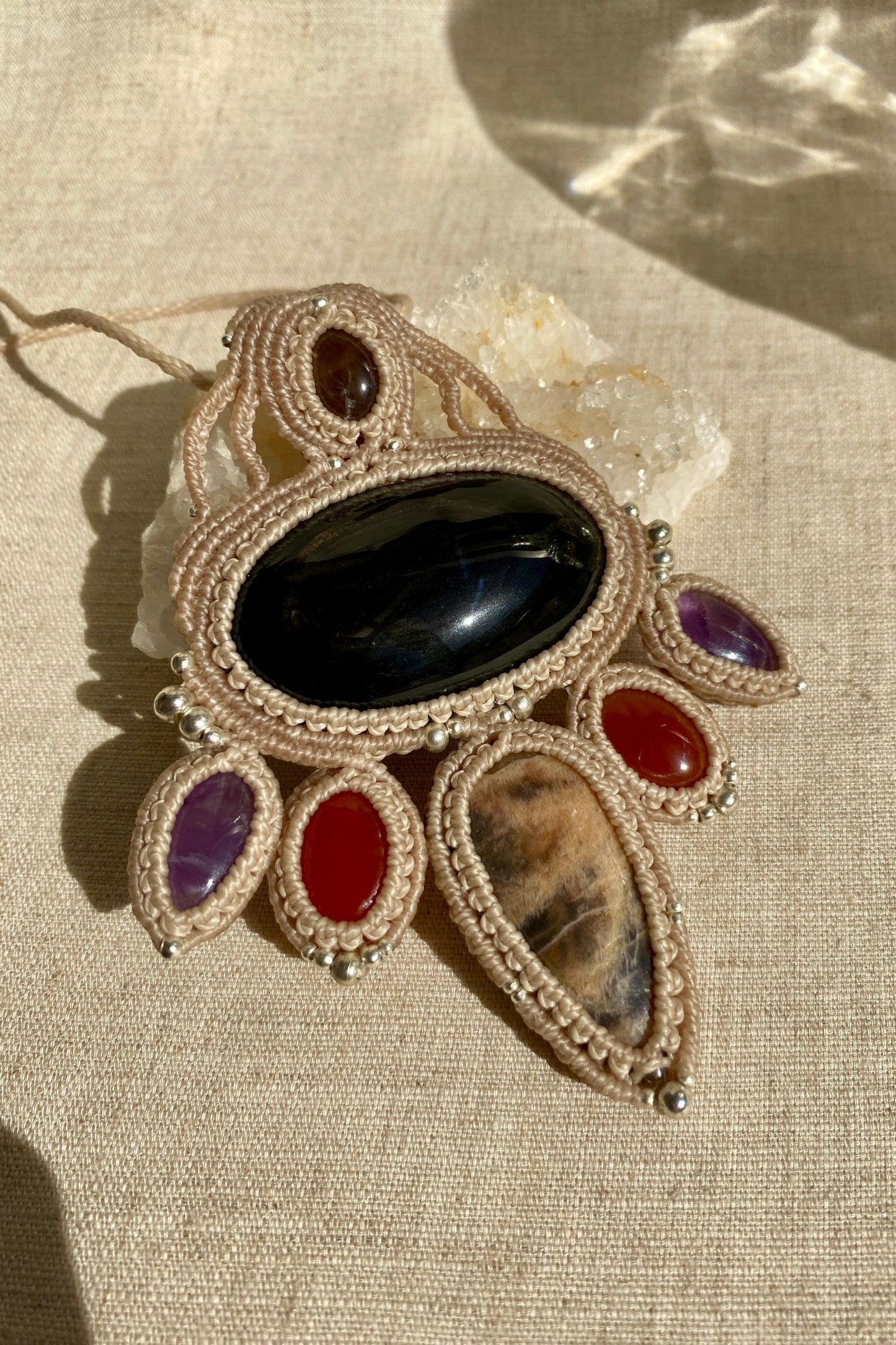 Side view of handmade macrame necklace with obsidian, black moonstone, smoky quartz, carnelian, and amethyst, showcasing detailed macrame work and gemstone arrangement.