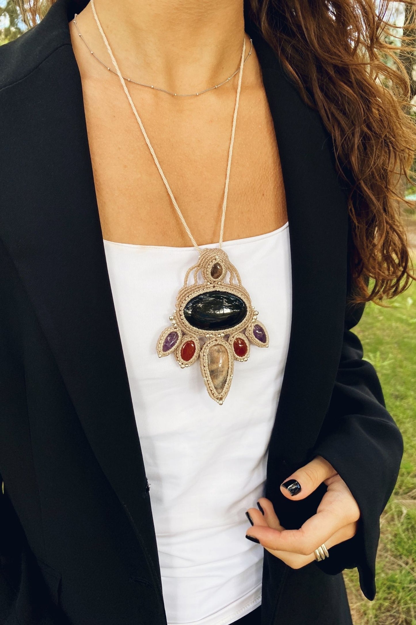 Model wearing a handmade macrame necklace with obsidian, black moonstone, smoky quartz, carnelian, and amethyst, showcasing the bold statement piece on the body.