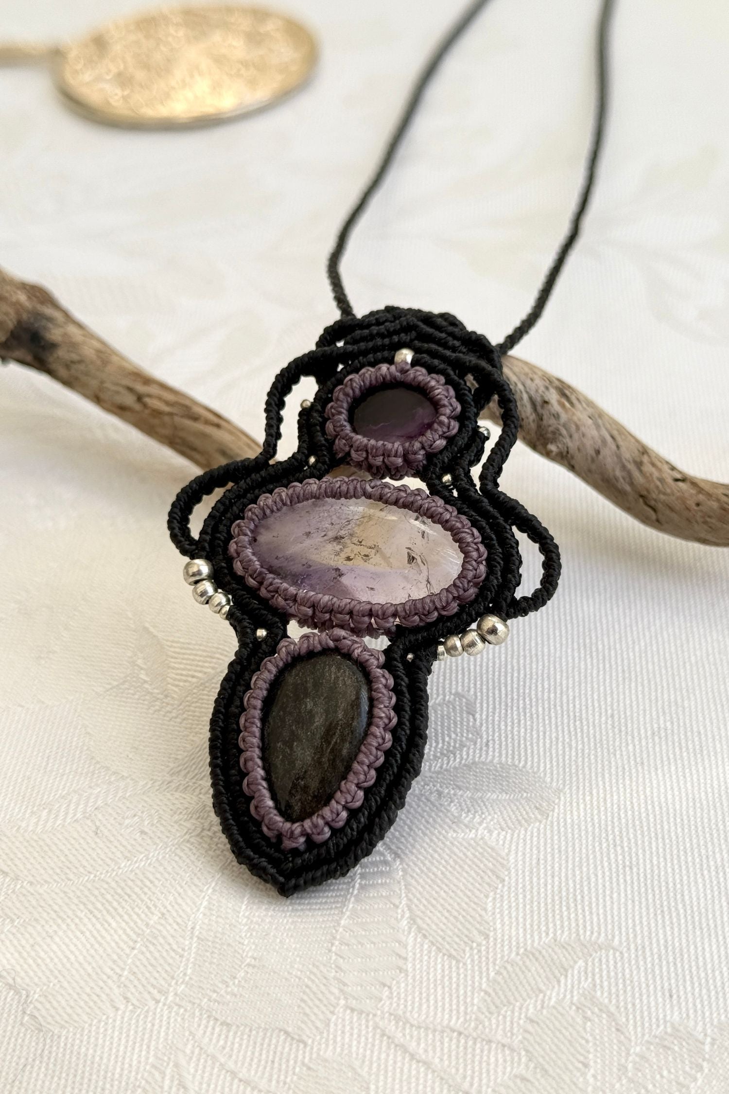 Another side-angle view of the handmade macrame necklace with Amethyst, Ametrine and Silver Sheen Obsidian. Showcasing depth, knotting details, and stone textures.
