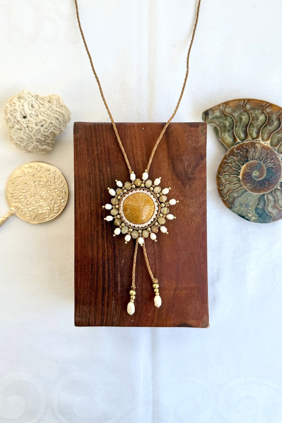 Close-up of fossilized sea urchin centerpiece on bolo tie with freshwater pearls and rutilated quartz beads highlighting intricate design