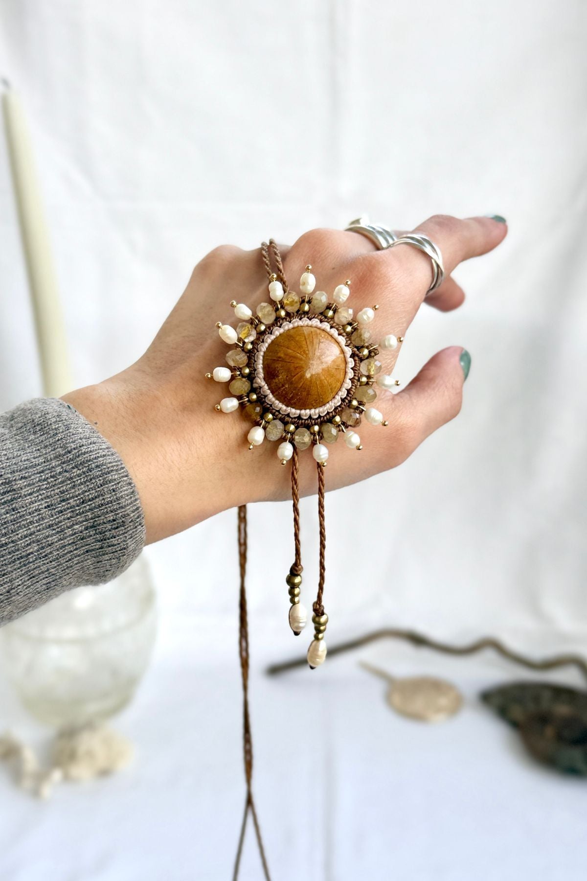 Hand holding sea urchin fossil bolo tie from the back, showing natural drape and artisan craftsmanship