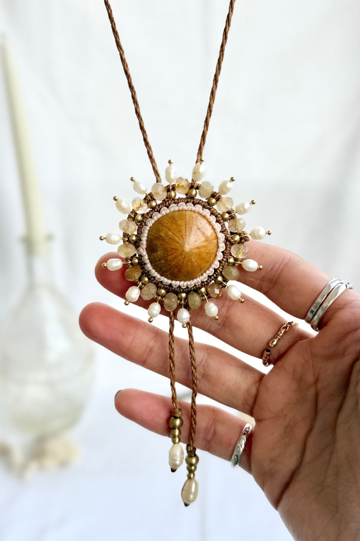 Close-up of fossilized sea urchin centerpiece on bolo tie with surrounding freshwater pearls and rutilated quartz