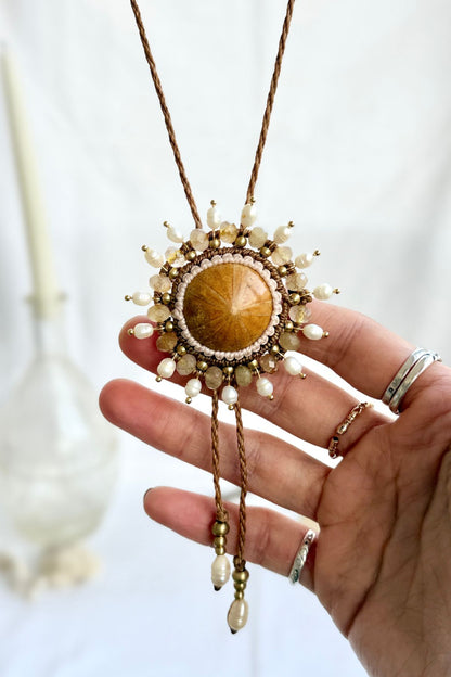 Close-up of fossilized sea urchin centerpiece on bolo tie with surrounding freshwater pearls and rutilated quartz