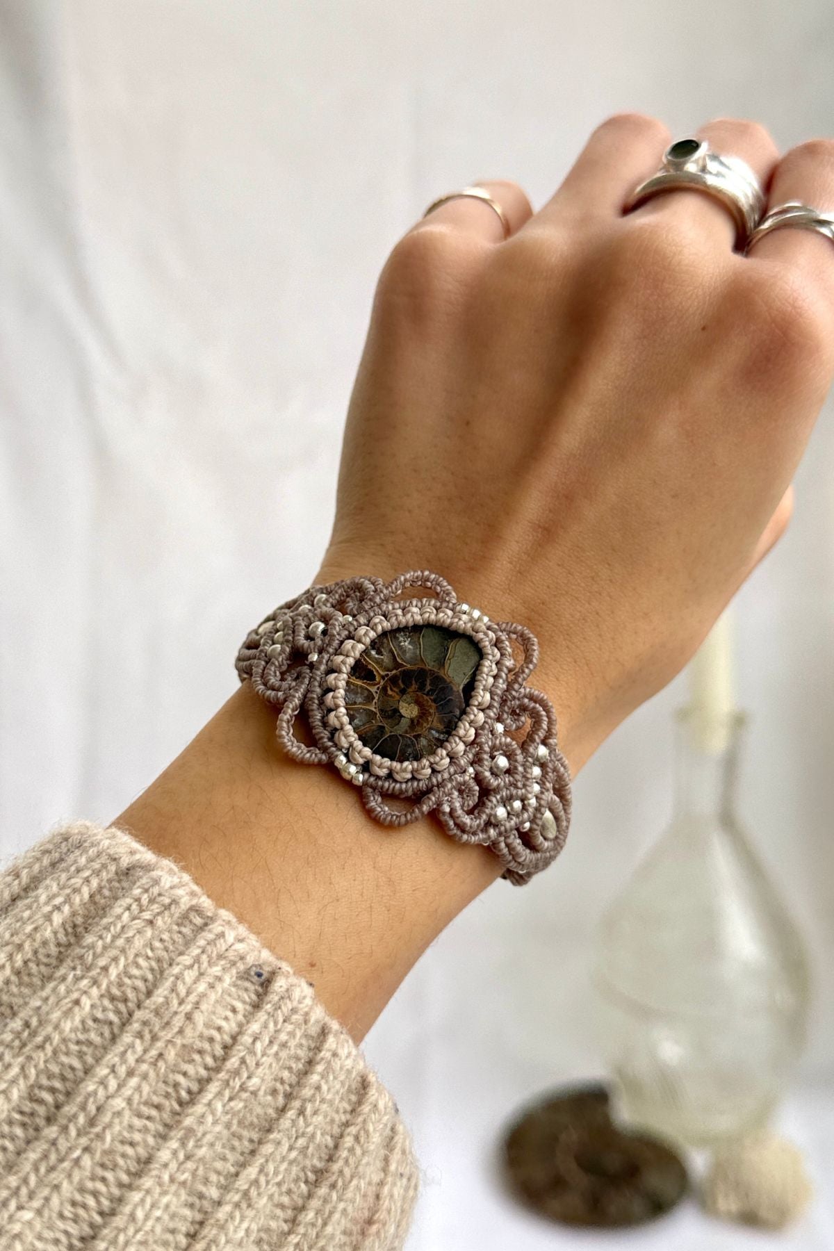 Ammonite cuff bracelet worn on wrist, featuring a sliced fossil centerpiece with natural translucency, one of a kind statement jewelry