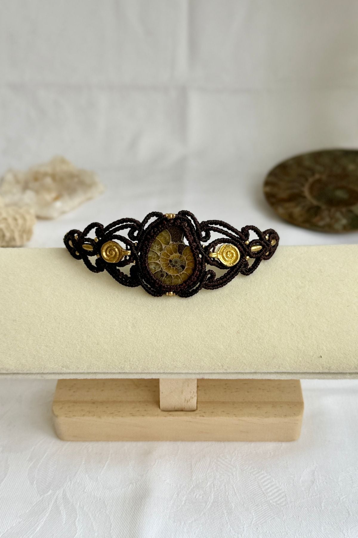 Yellow ammonite cuff bracelet shown from a distance to highlight proportions and bold spiral fossil centerpiece