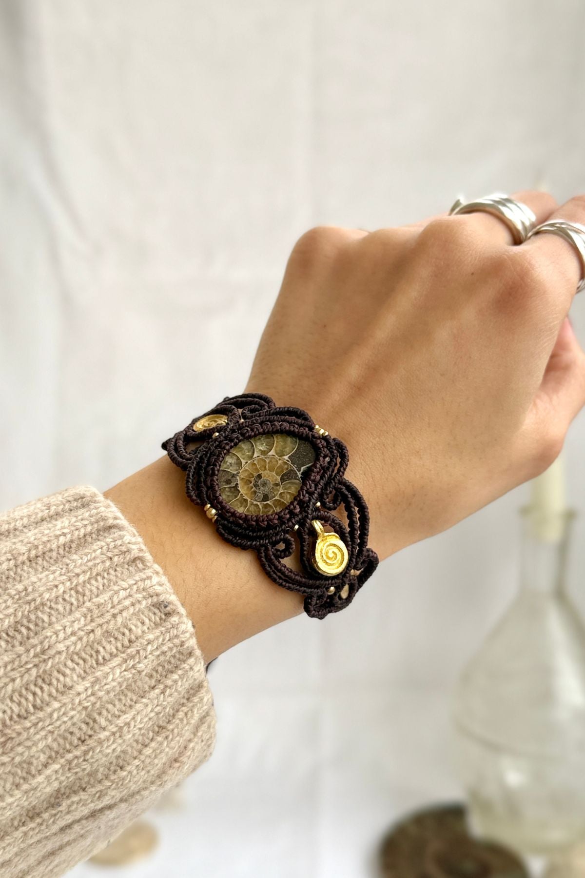 Yellow ammonite spiral cuff bracelet on wrist, showcasing warm fossil tones and brass spiral accents