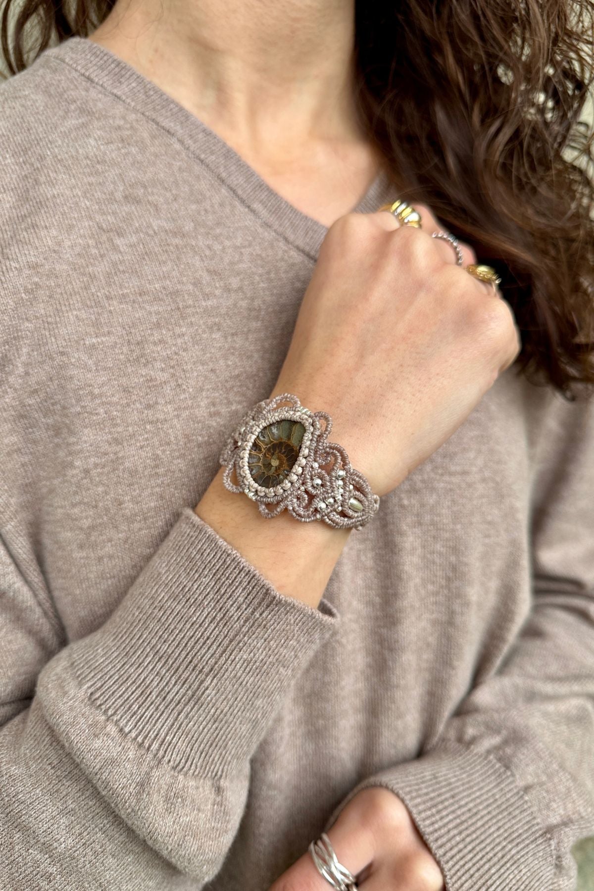 Close view of ammonite cuff bracelet on model, highlighting fossil centerpiece and elegant open design