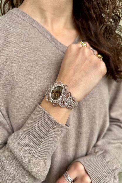 Close view of ammonite cuff bracelet on model, highlighting fossil centerpiece and elegant open design