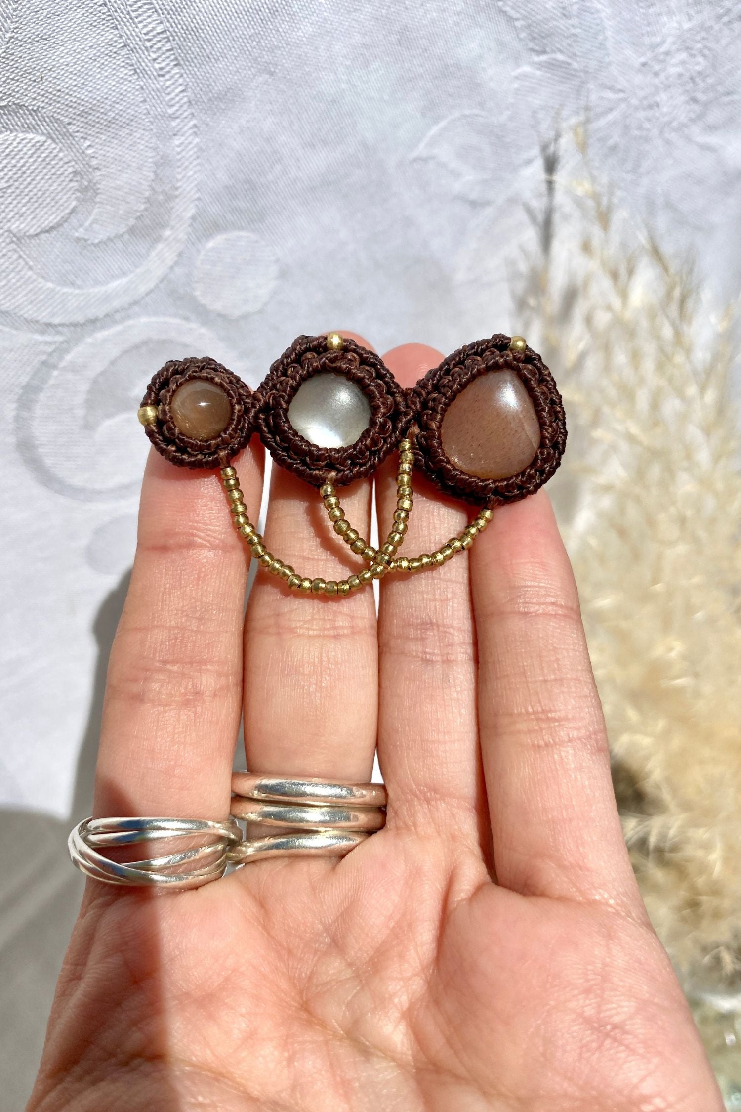 Handmade statement brooch held in hand, giving a sense of its size and the detailed craftsmanship of the Peach Moonstone gemstones.