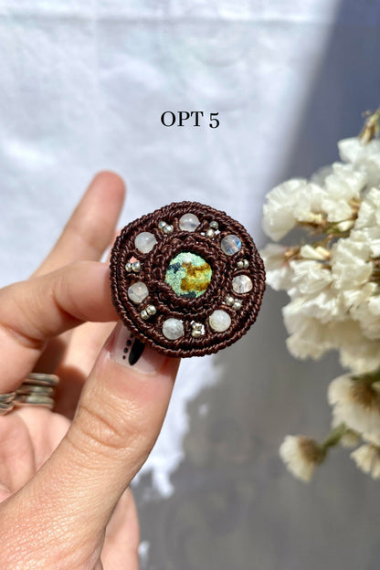 Handmade turquoise brooch with a round design, held in hand to showcase its size, shape, and natural stone details.