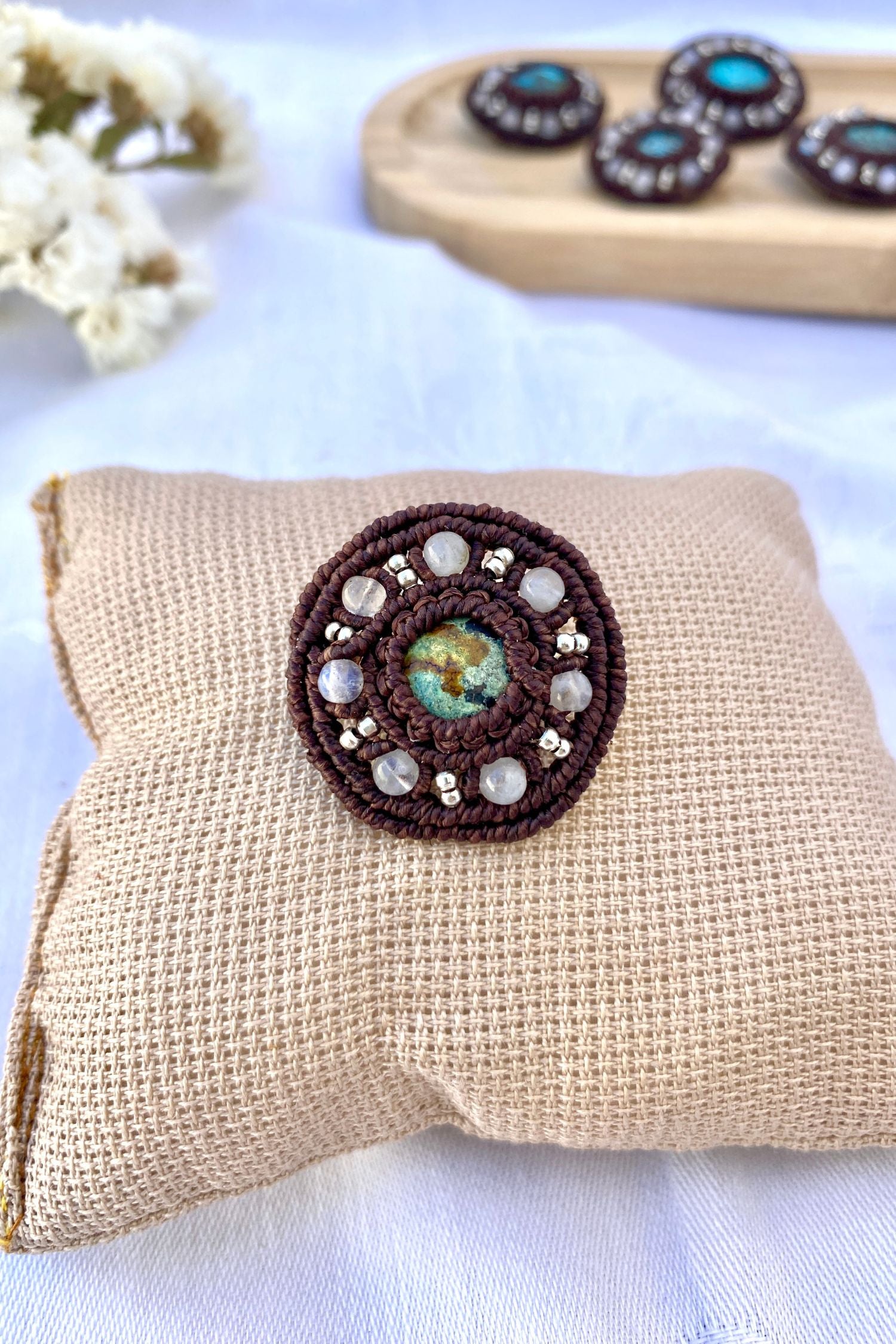 Close-up of the vibrant turquoise gemstone and moonstone bead accents in this handcrafted macrame brooch, highlighting its unique natural variations.