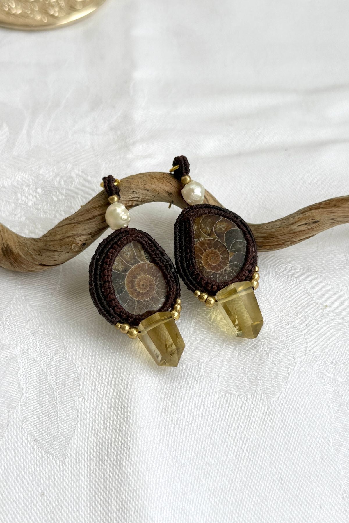 Close-up of sliced ammonite with smoky quartz point and freshwater pearl, highlighting intricate design and natural fossil beauty