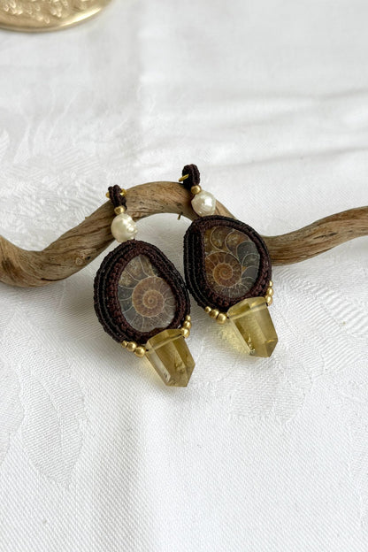 Close-up of sliced ammonite with smoky quartz point and freshwater pearl, highlighting intricate design and natural fossil beauty