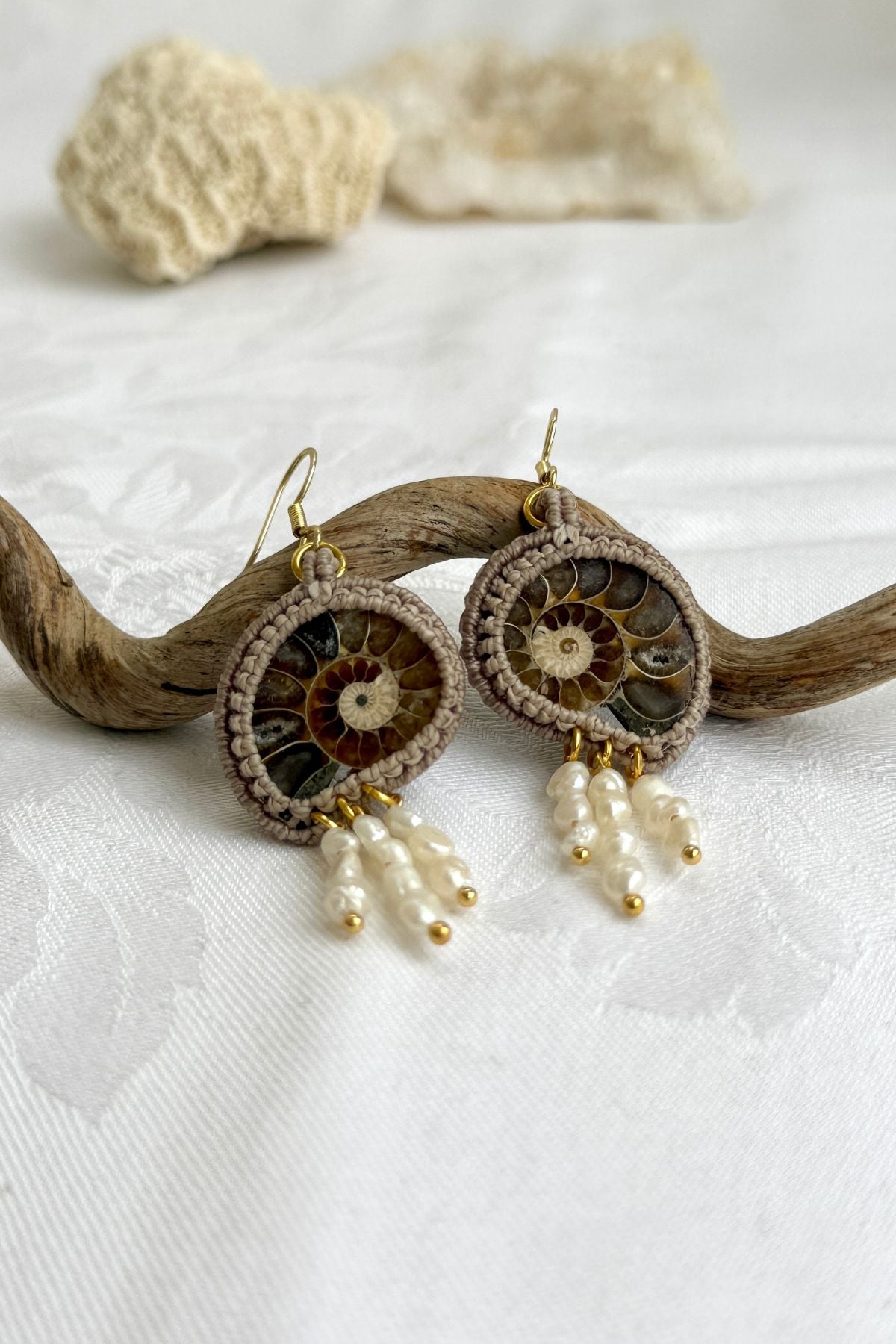 Close-up of sliced ammonite fossil with dangling freshwater pearls, showcasing intricate craftsmanship
