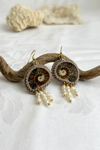 Close-up of sliced ammonite fossil with dangling freshwater pearls, showcasing intricate craftsmanship